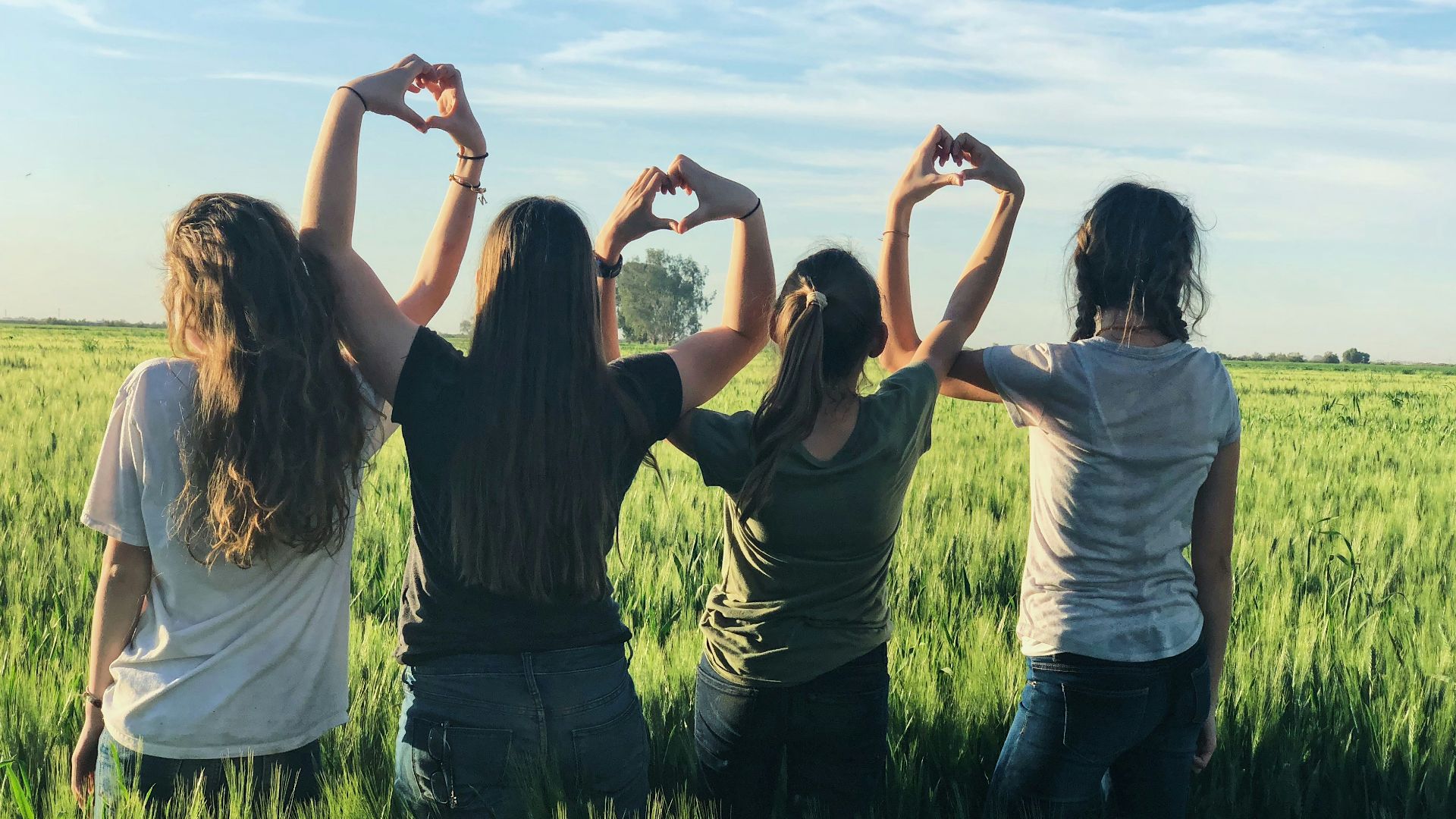women forming heart gestures during daytime
