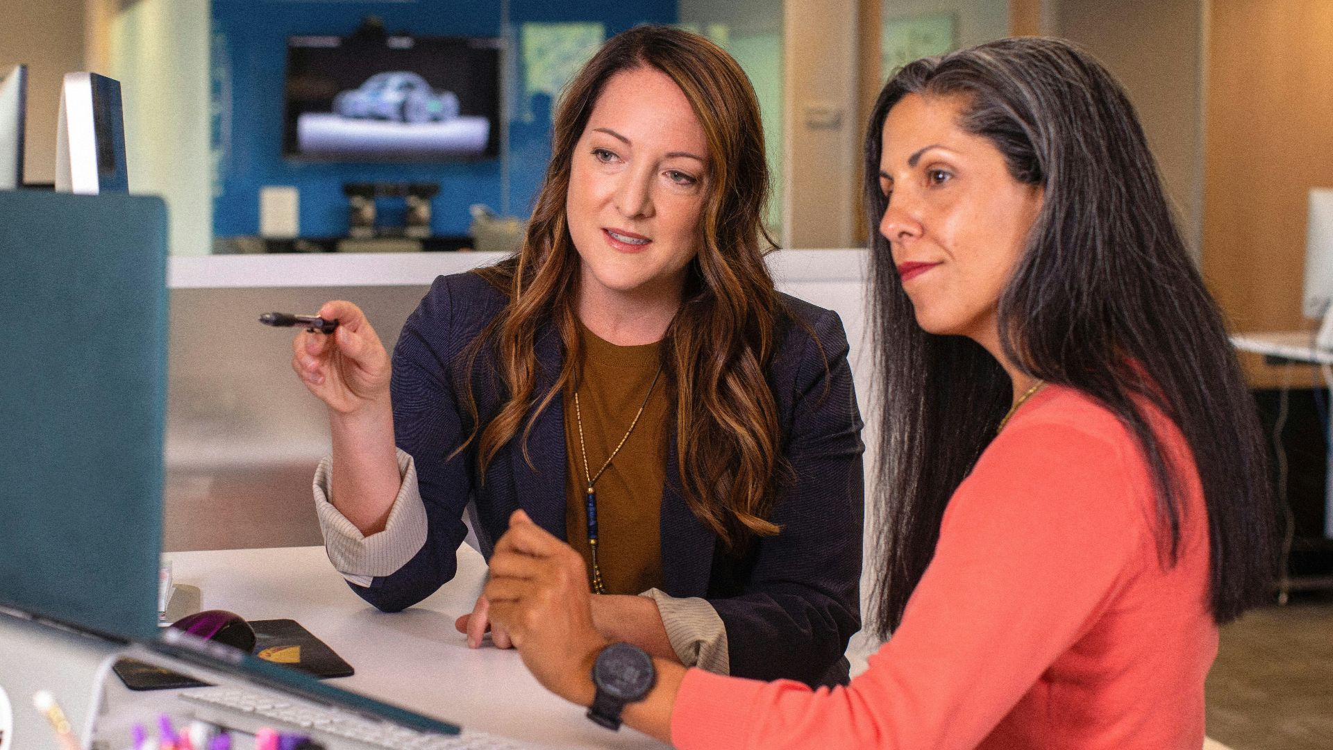 two women sitting at a table looking at a computer screen