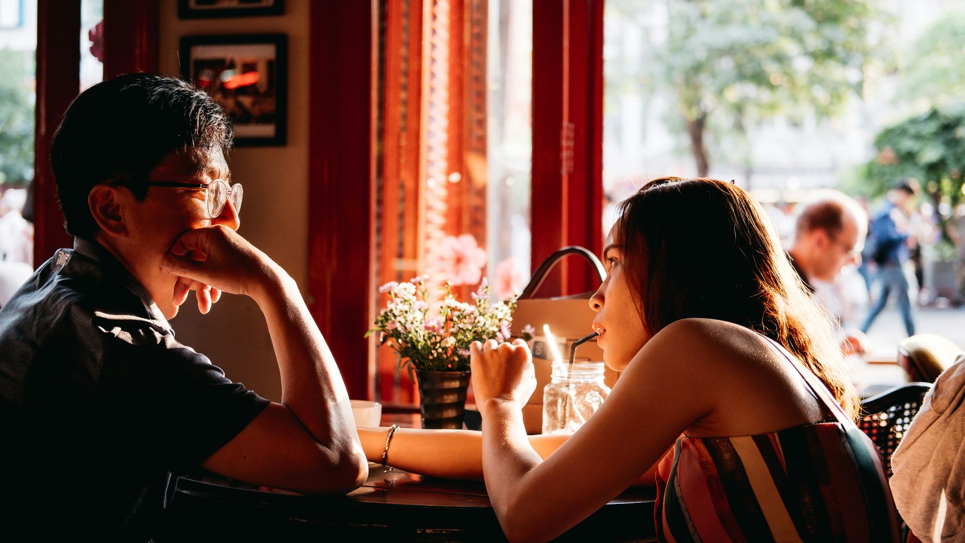 man wearing black collared top sitting on chair in front of table and woman wearing multicolored top