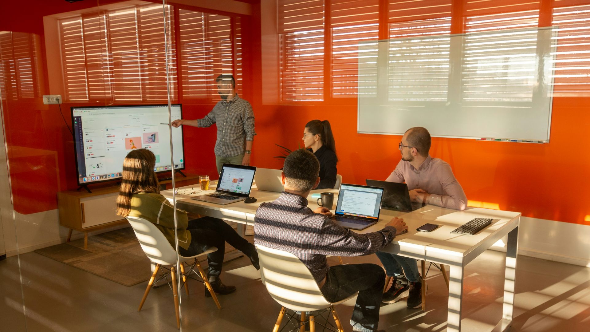a group of people sitting around a table with laptops