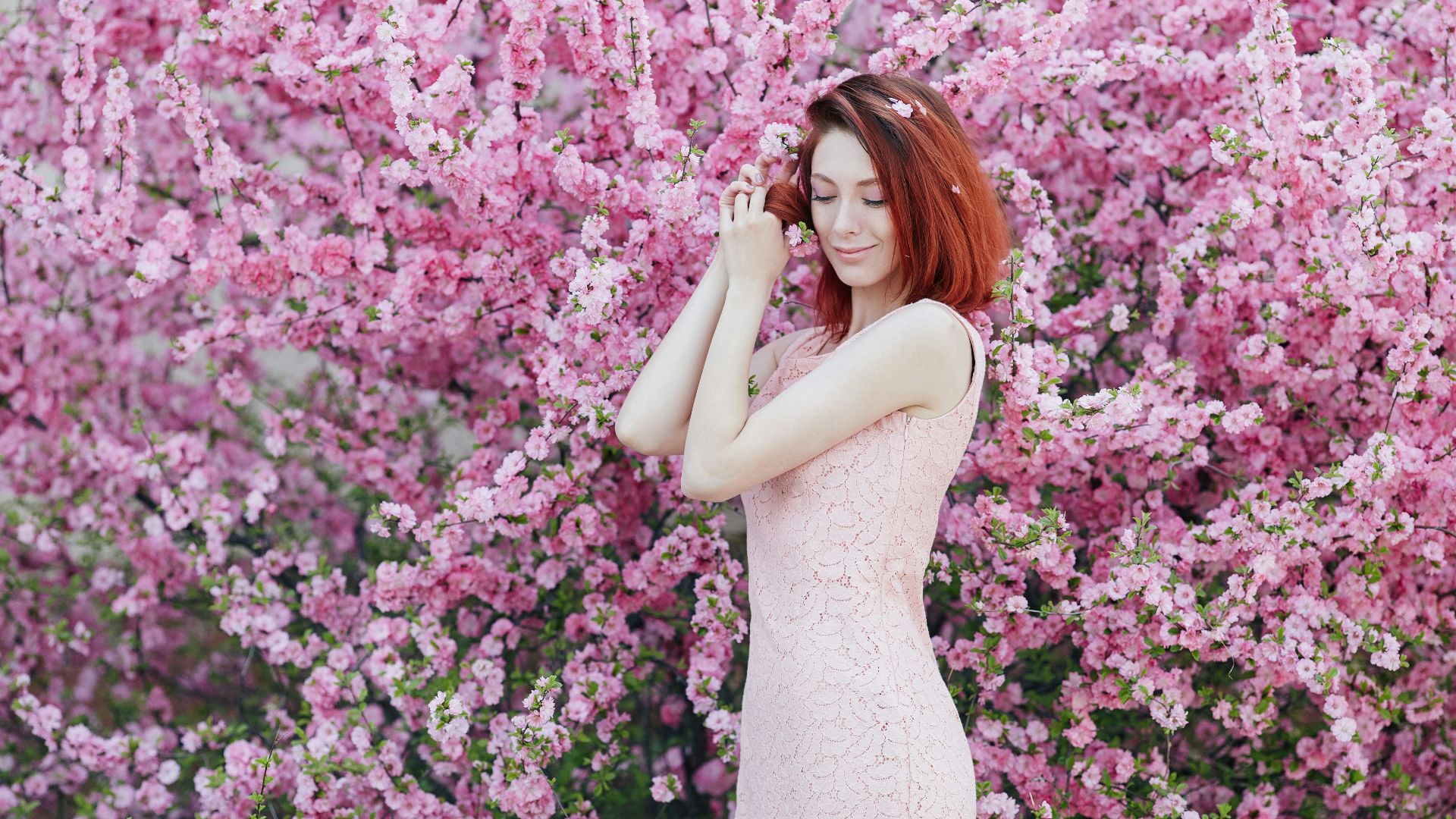 woman in white sleeveless dress standing beside pink flowers
