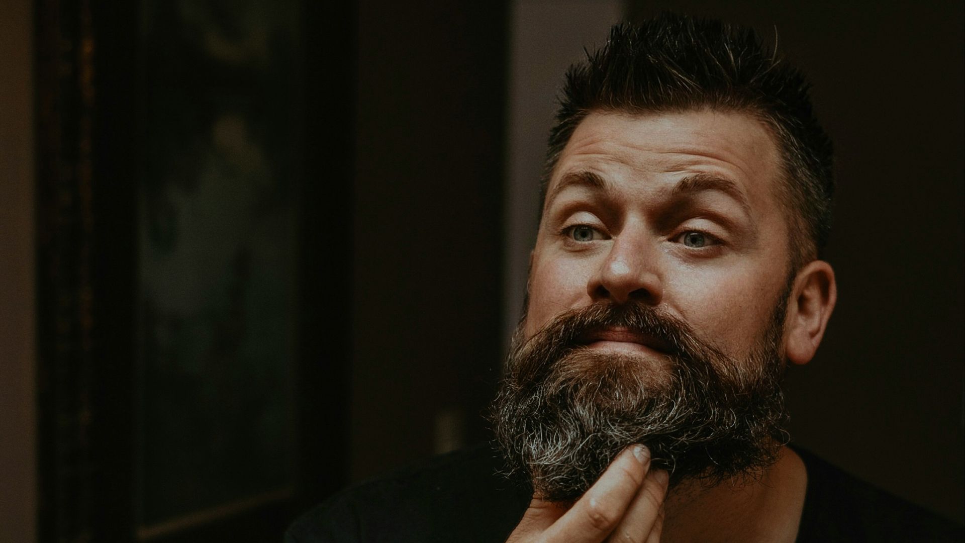 a man is shaving his beard in the mirror