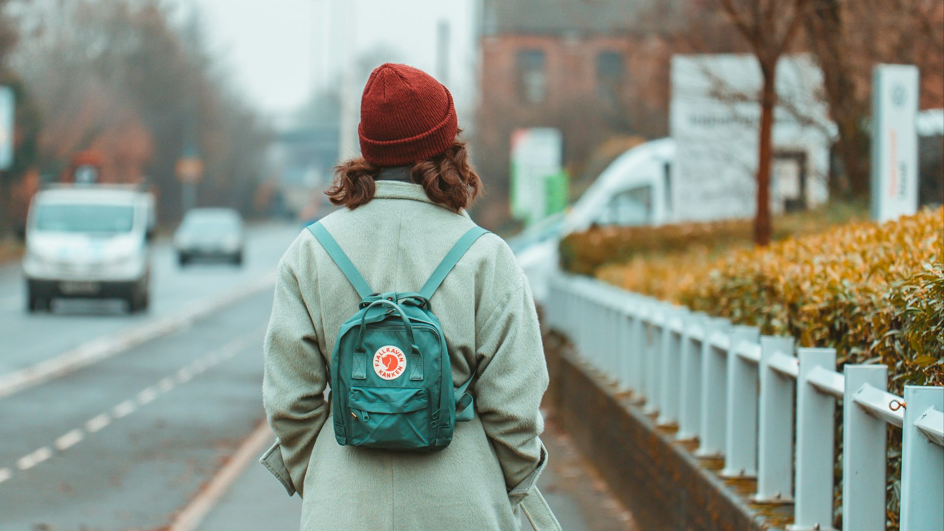 a woman walking down a street with a backpack on her back