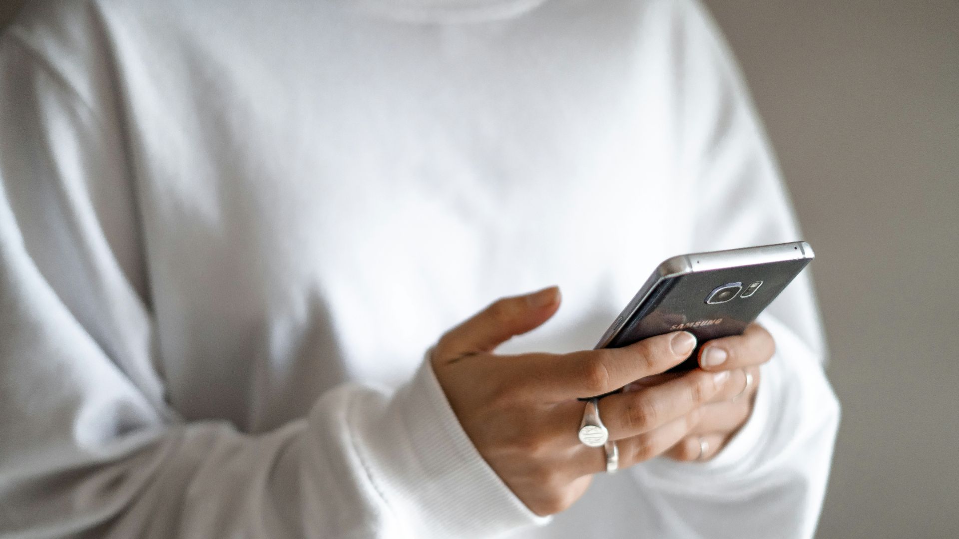 person in white long sleeve shirt holding black smartphone