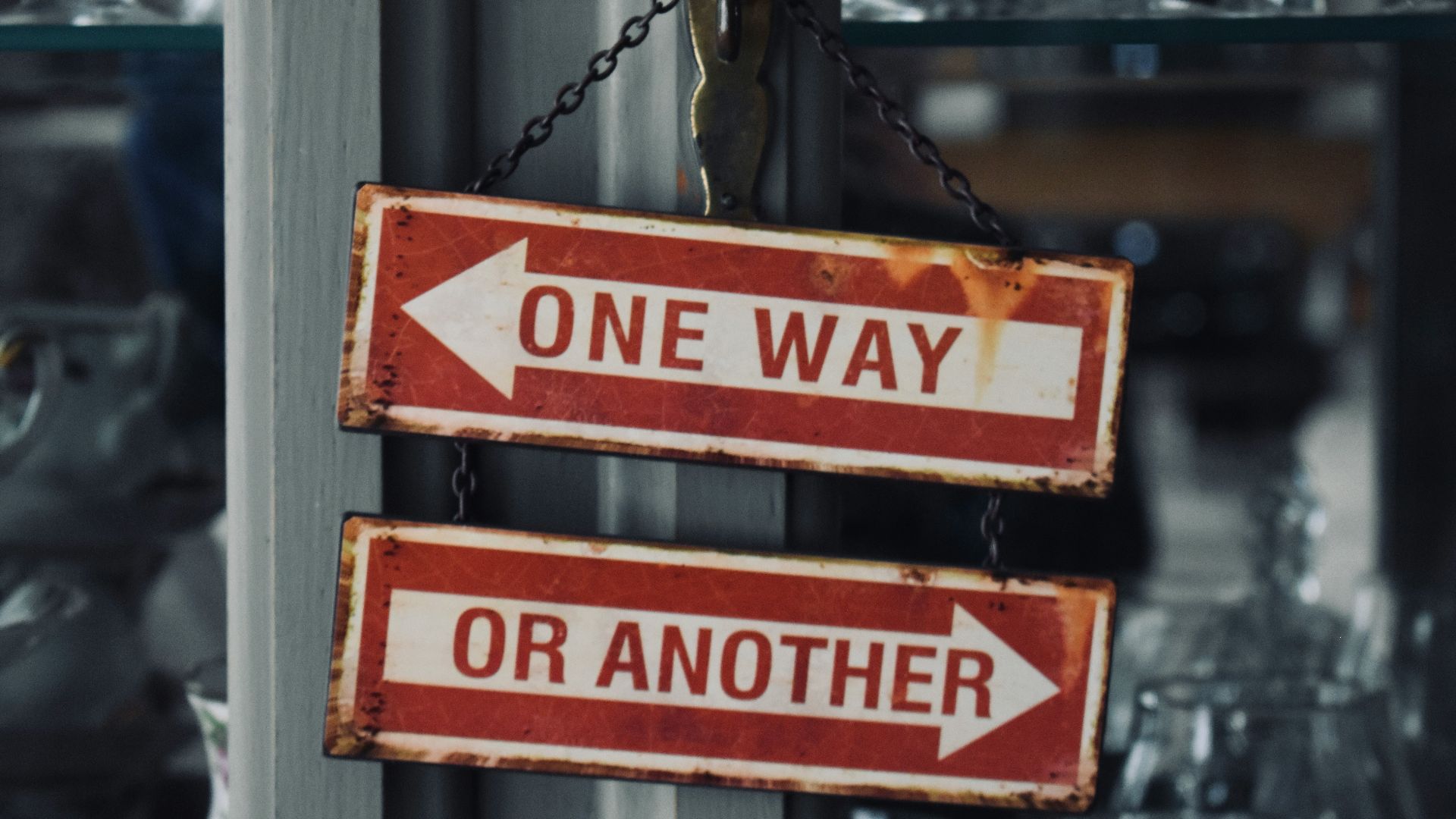 two red and white signs hanging from a metal pole