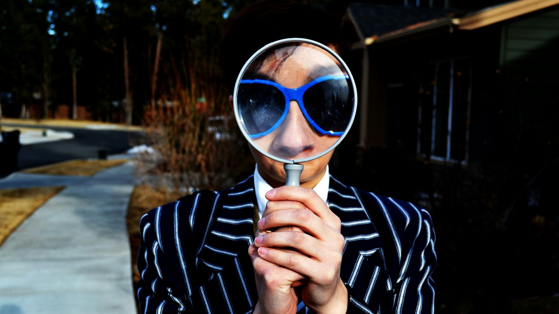 person using magnifying glass enlarging the appearance of his nose and sunglasses