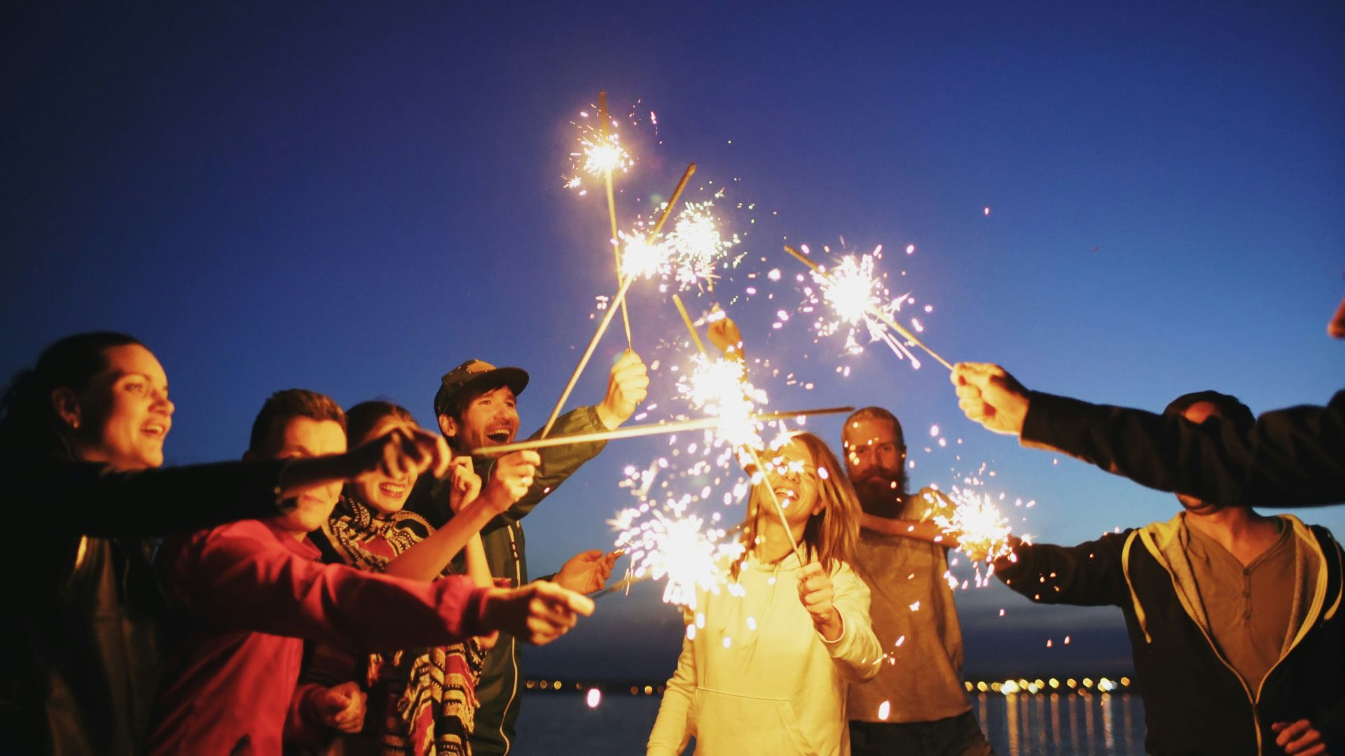 Friends celebrating with sparklers at dusk