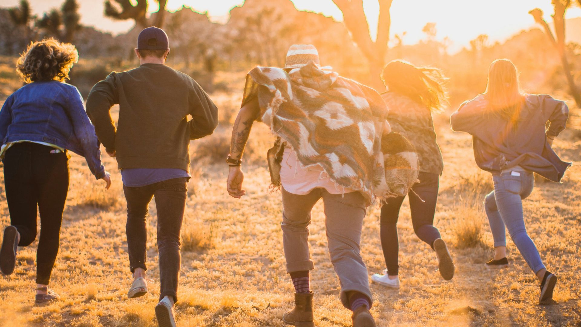 fiver person running on the field near trees