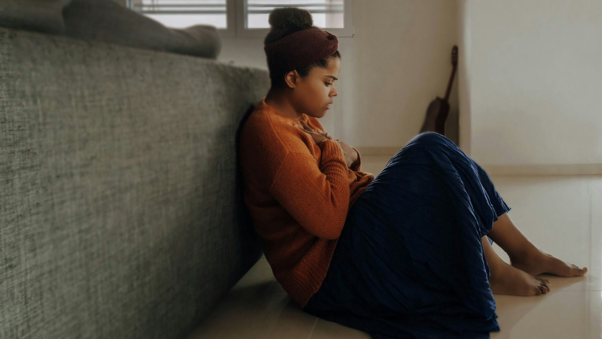 man in orange long sleeve shirt sitting on gray couch