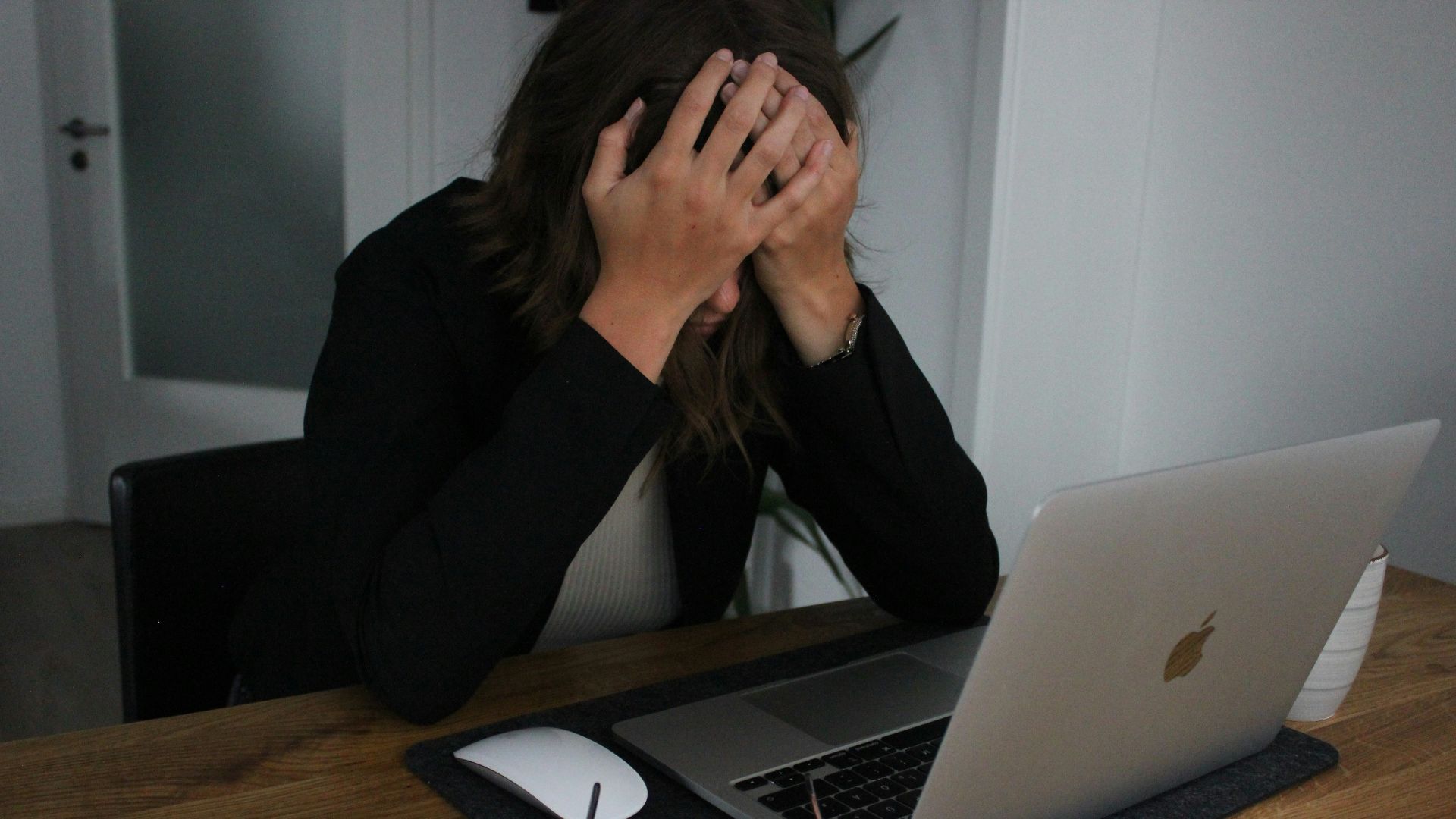 a woman covering her face while looking at a laptop