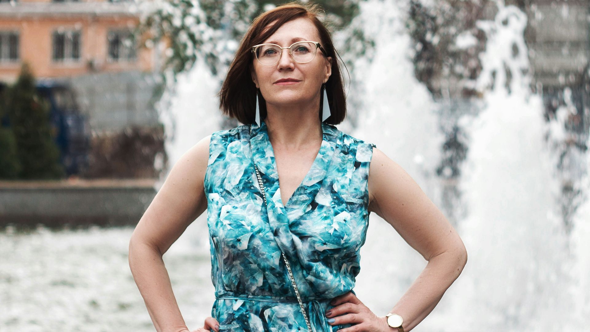 woman in blue and white floral sleeveless dress standing on snow covered ground during daytime