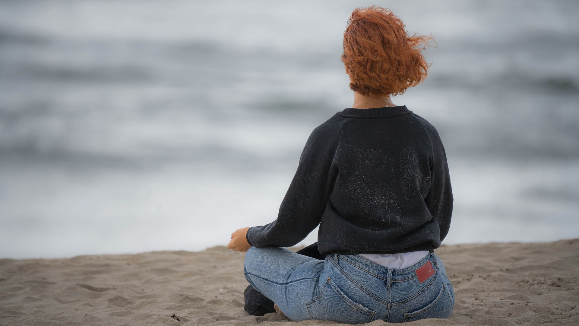 a woman sitting in the sand on the beach