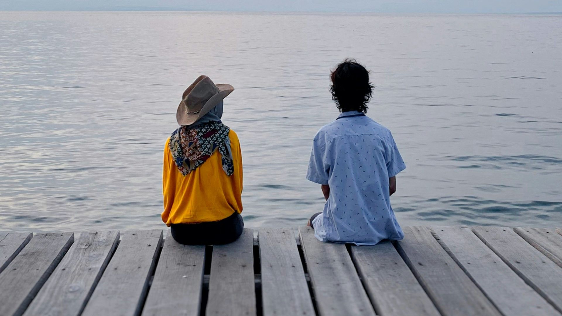 woman in yellow jacket sitting on wooden dock during daytime