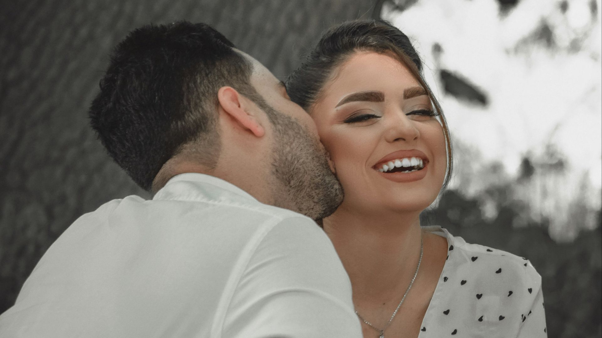 man in white dress shirt hugging woman in white and black polka dot dress