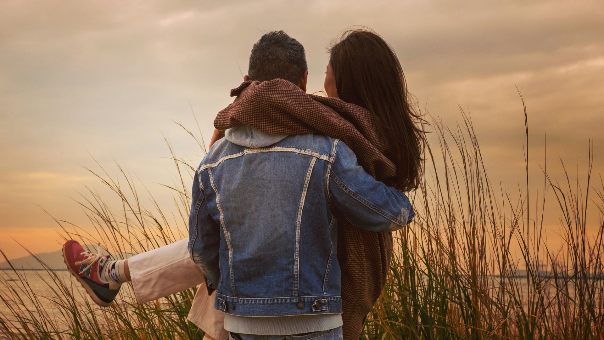 woman in blue denim jacket and blue denim jeans standing on green grass field during daytime