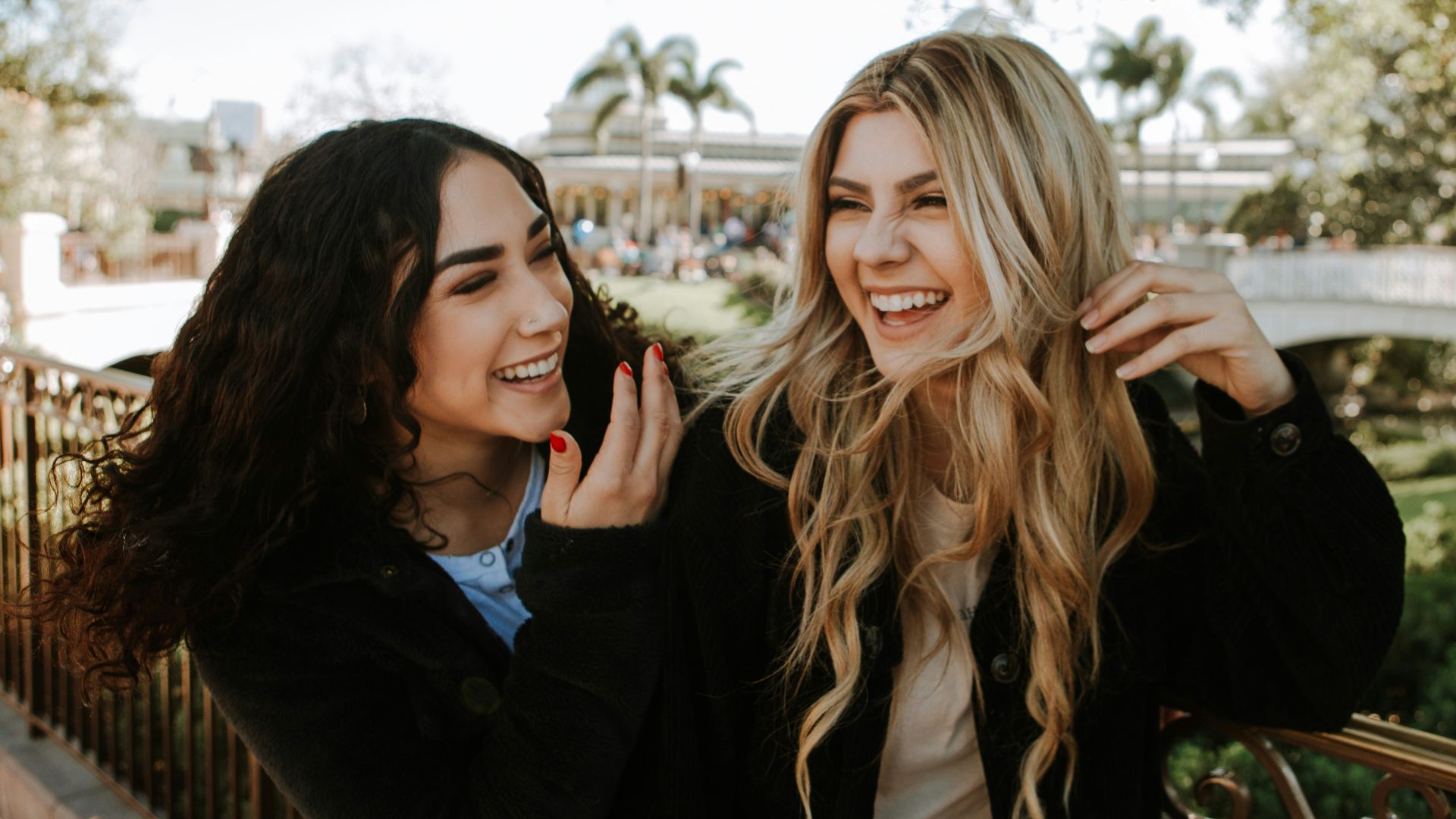 2 women smiling and standing near trees during daytime
