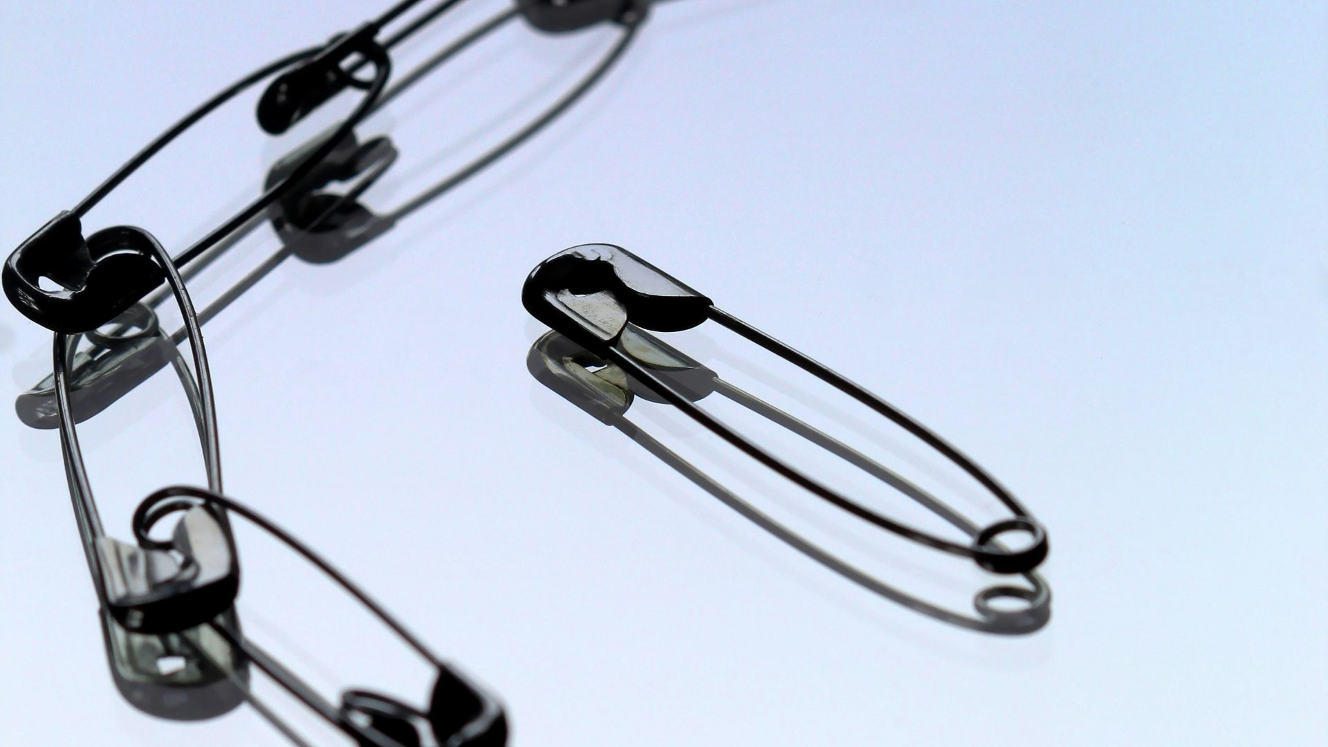 silver safety pin on white paper