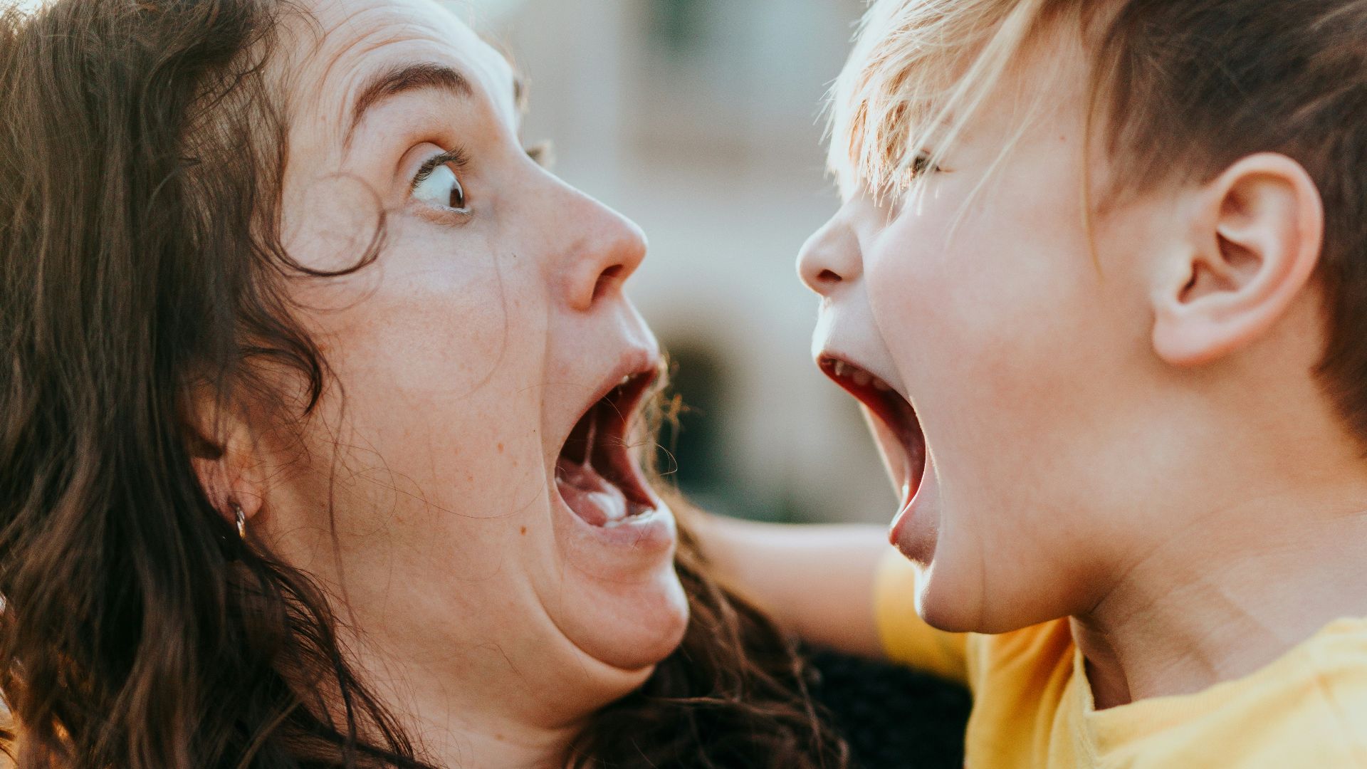 woman in black sweater kissing girl in yellow shirt