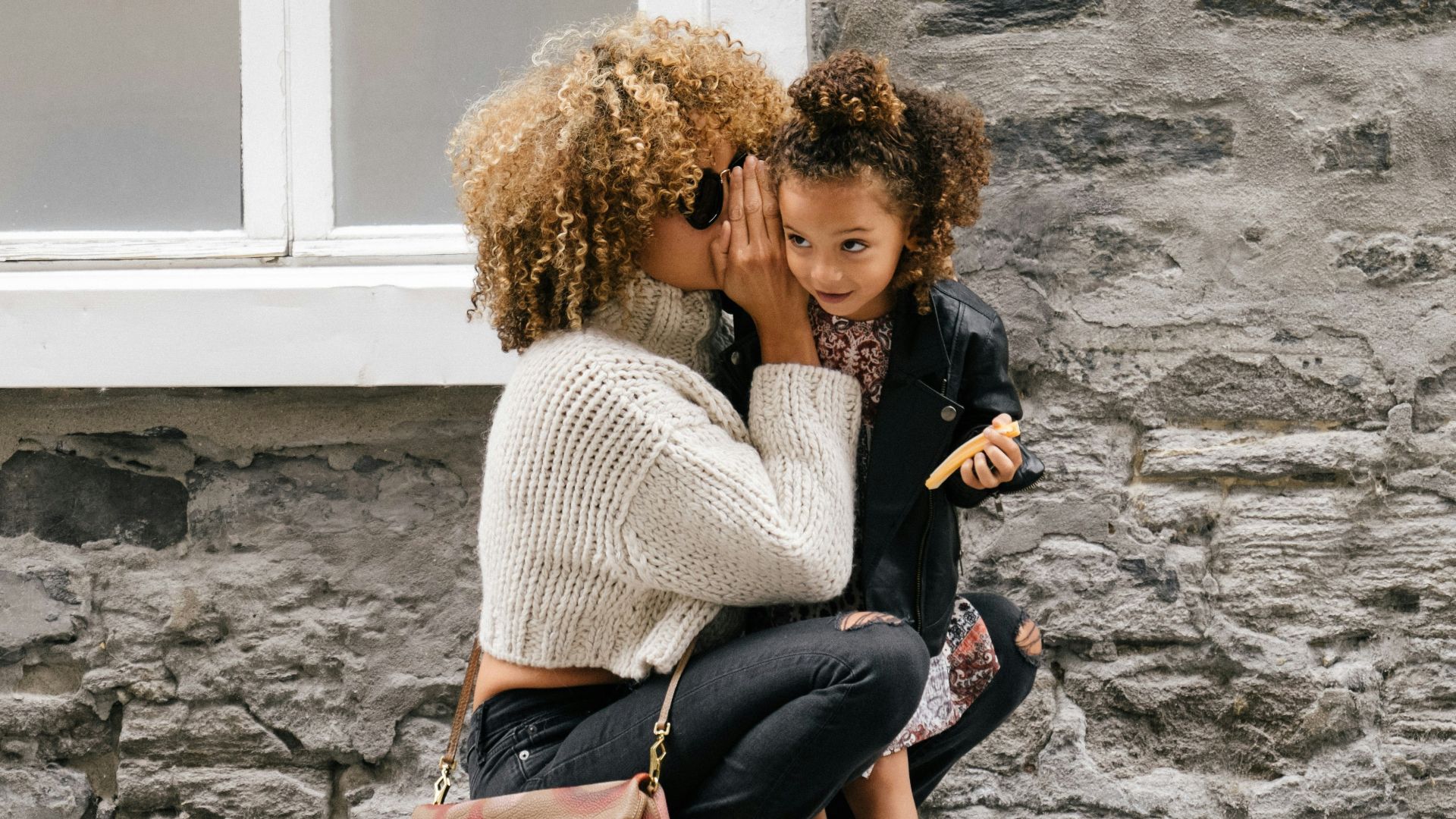 woman wearing white sweater carrying a daughter