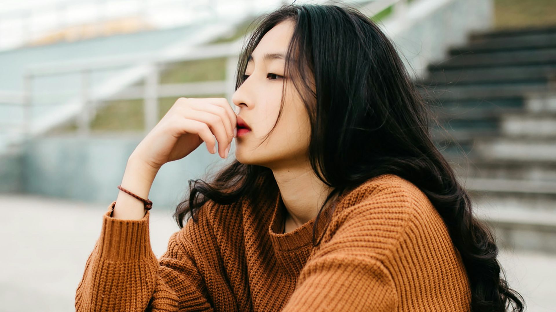 woman wearing brown sweater holding lips