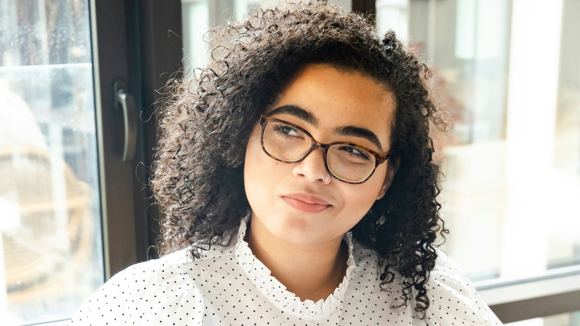 woman in white and black polka dot shirt holding blue and white book