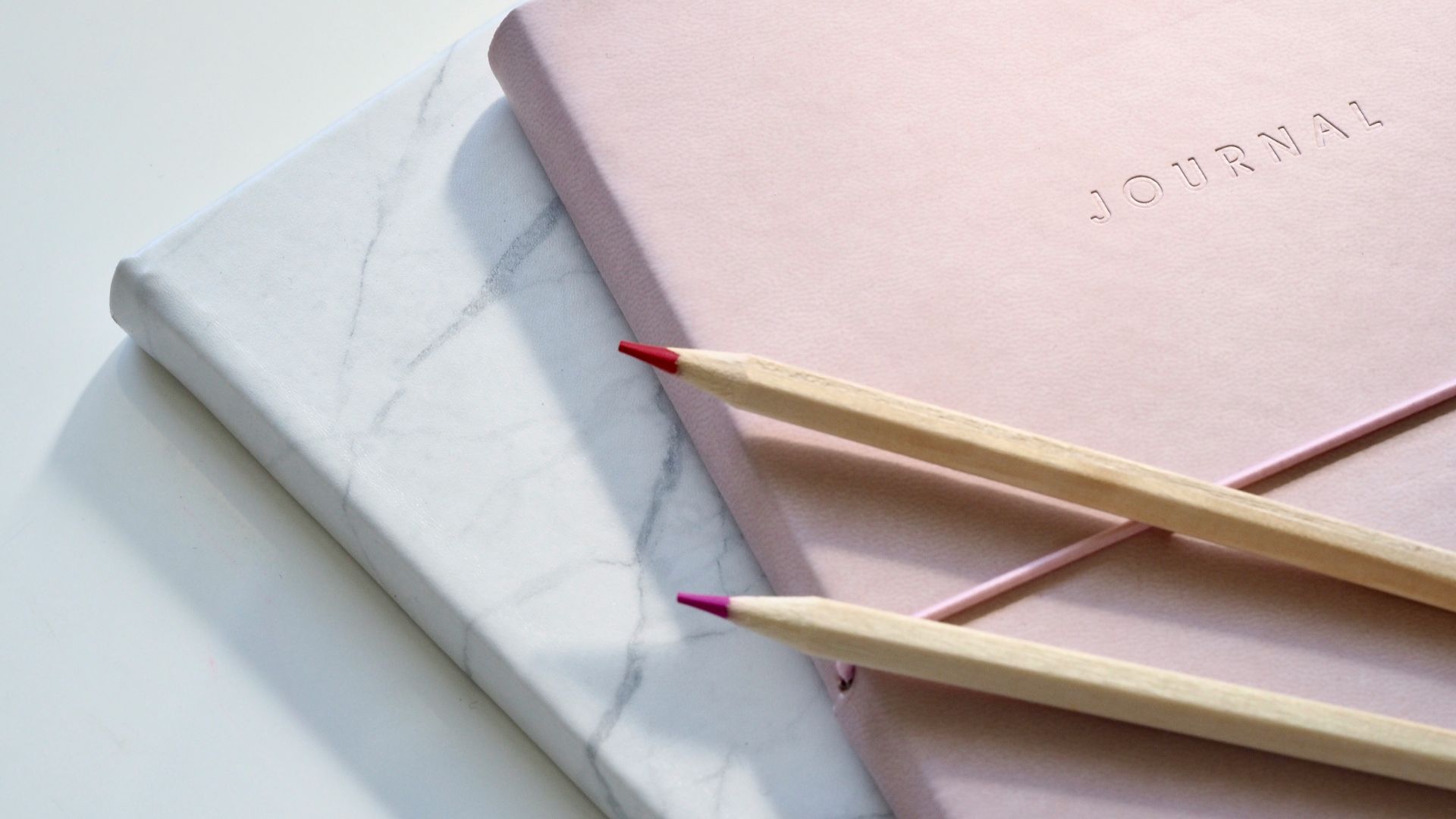 red and purple coloring pencils on pink journal