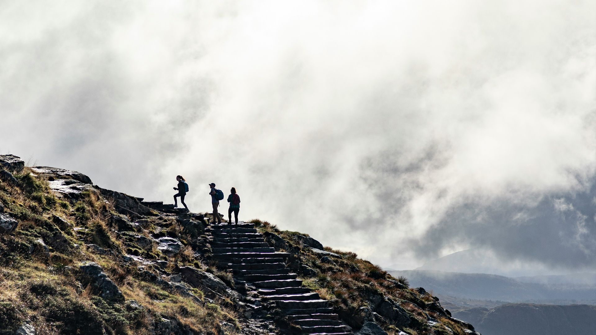 person standing on rocky mountain under cloudy sky during daytime