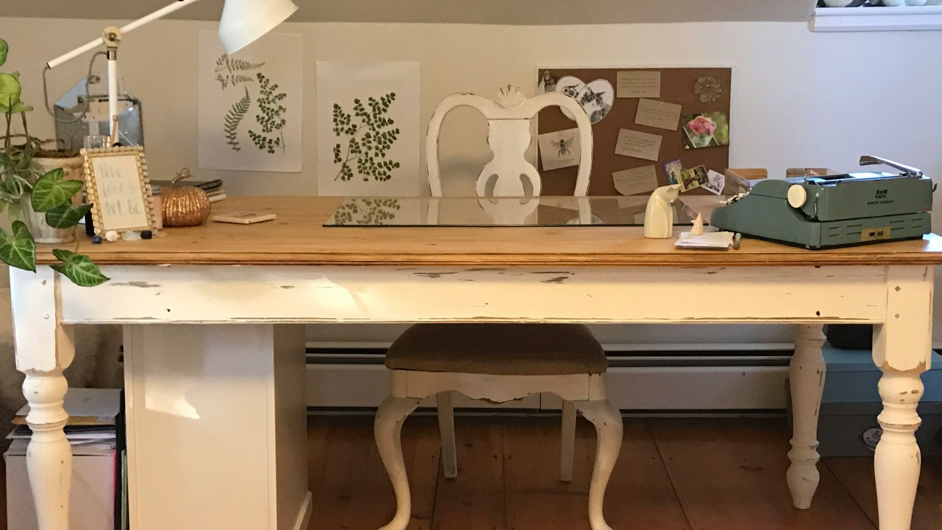 a room with a desk, chair, lamp and pictures on the wall