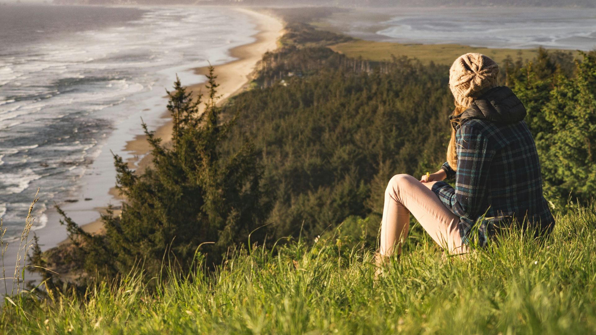 person sitting on hill near ocean during daytime