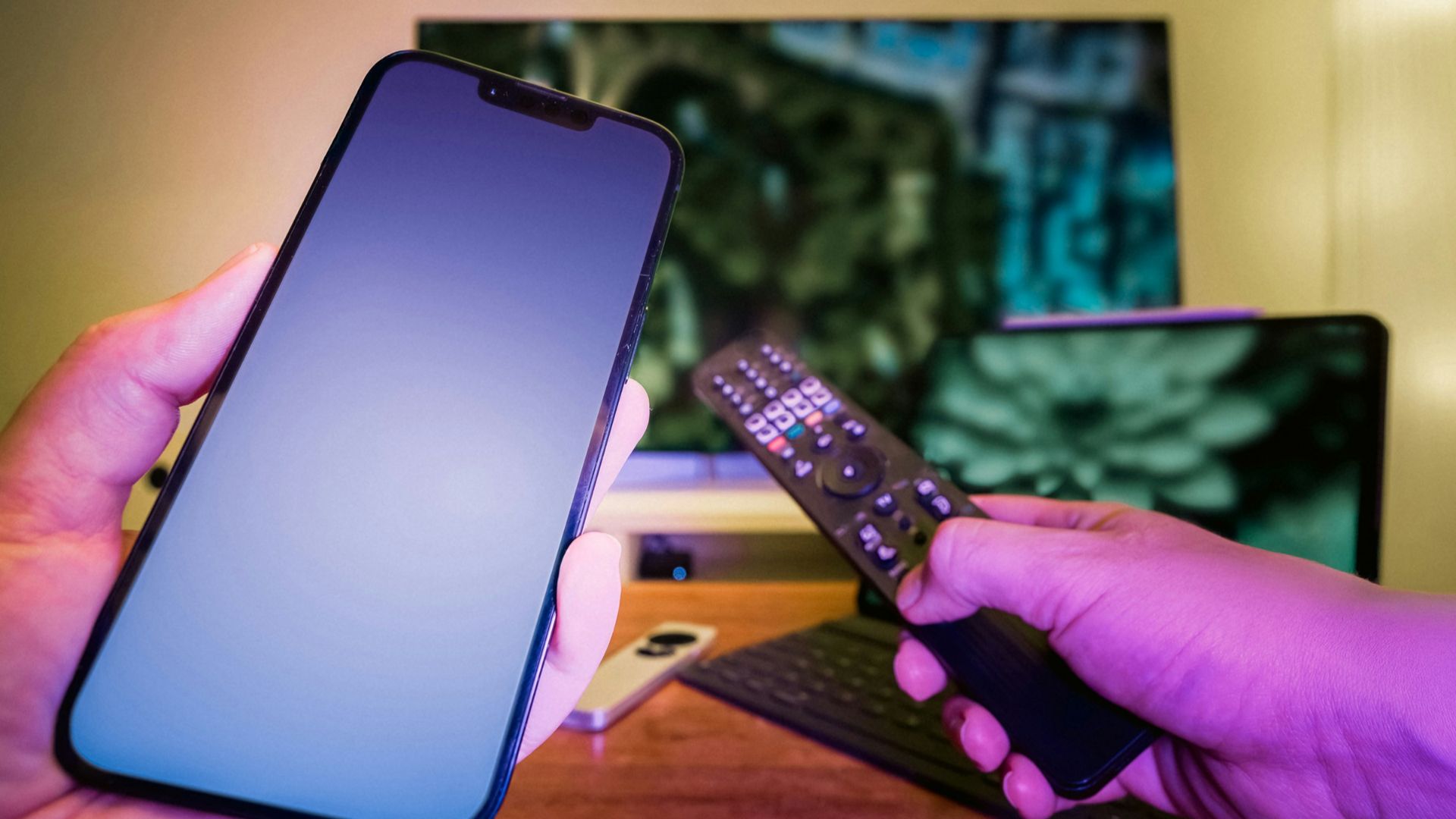 A person holding a cell phone and a remote control