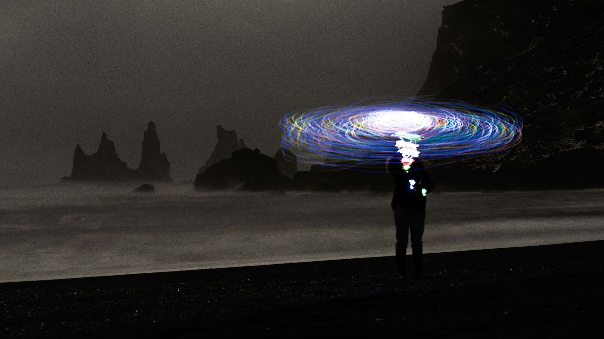a man standing on top of a beach under a light painting