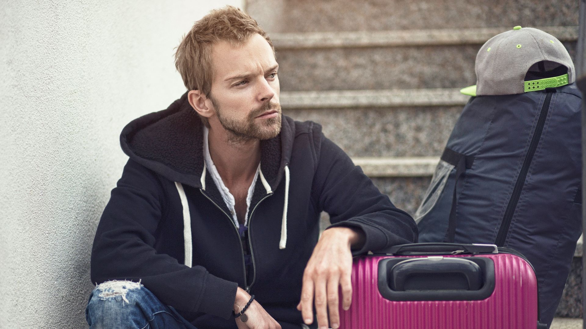 a man sitting next to a purple suitcase