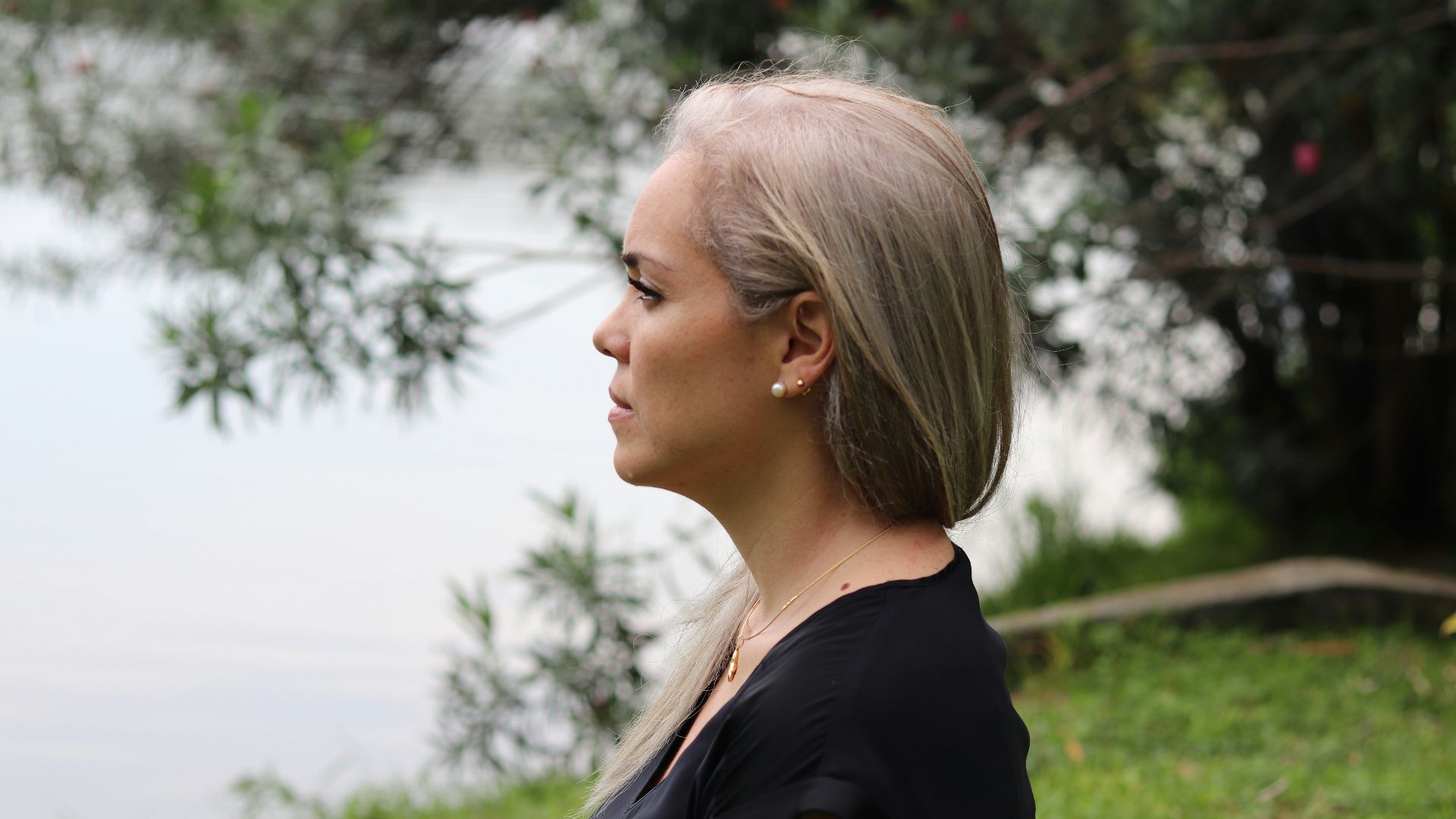 a woman with blonde hair standing in front of a body of water