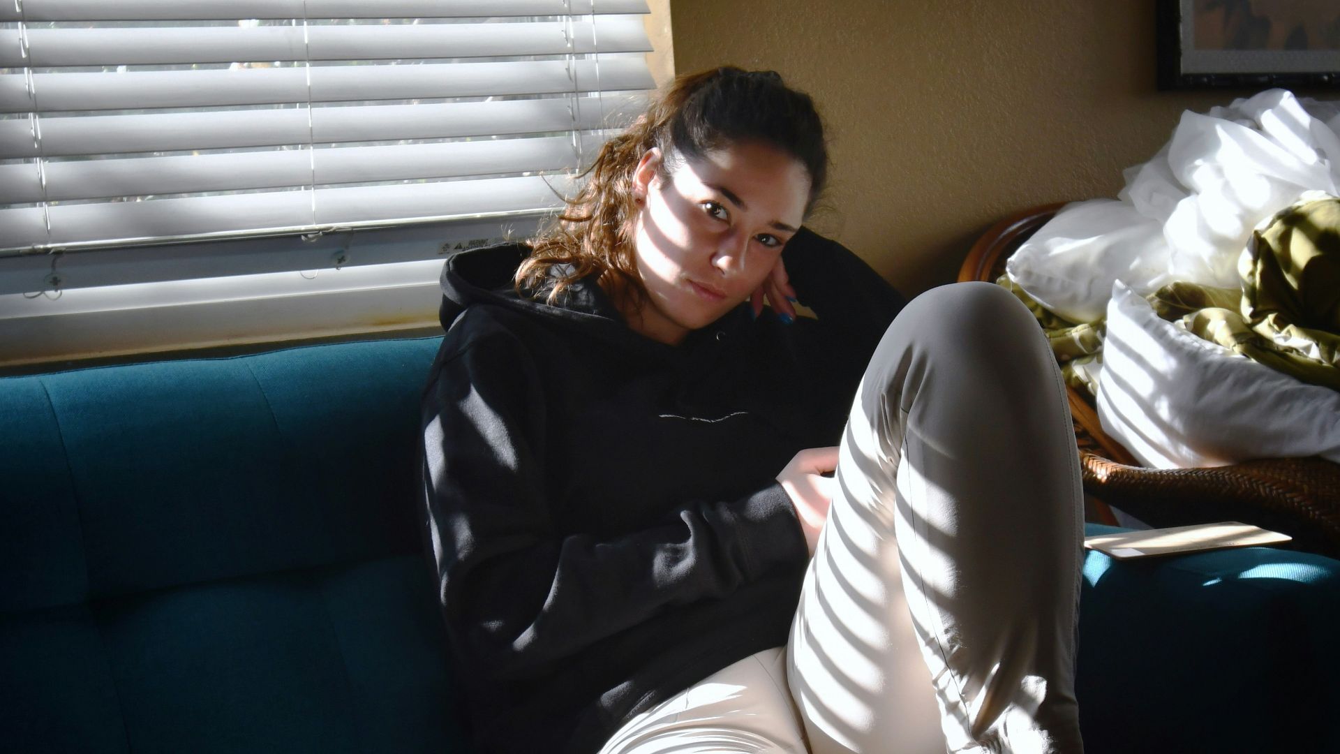 a woman sitting on a blue couch in front of a window