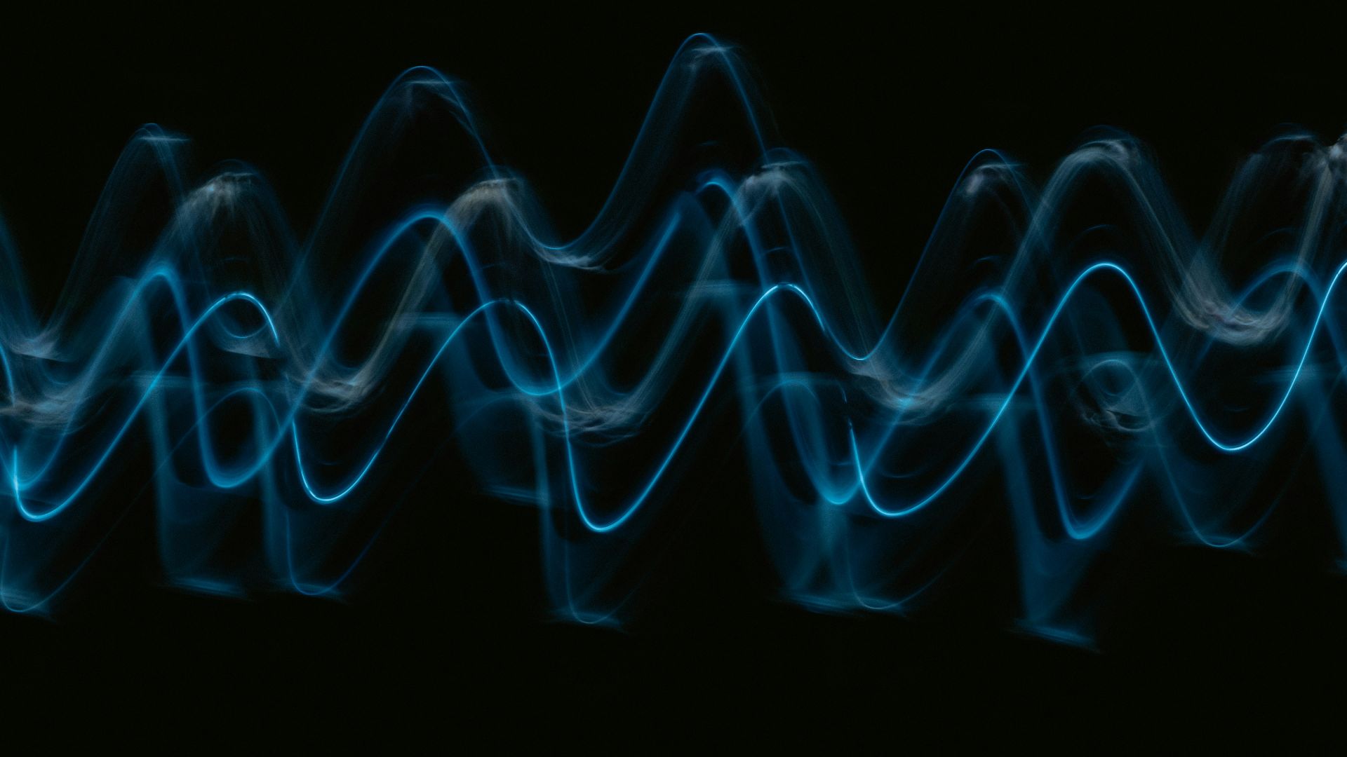 a black background with a blue wave of light