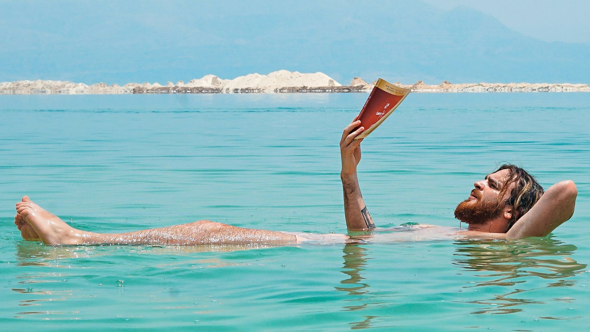 person on body of water reading book
