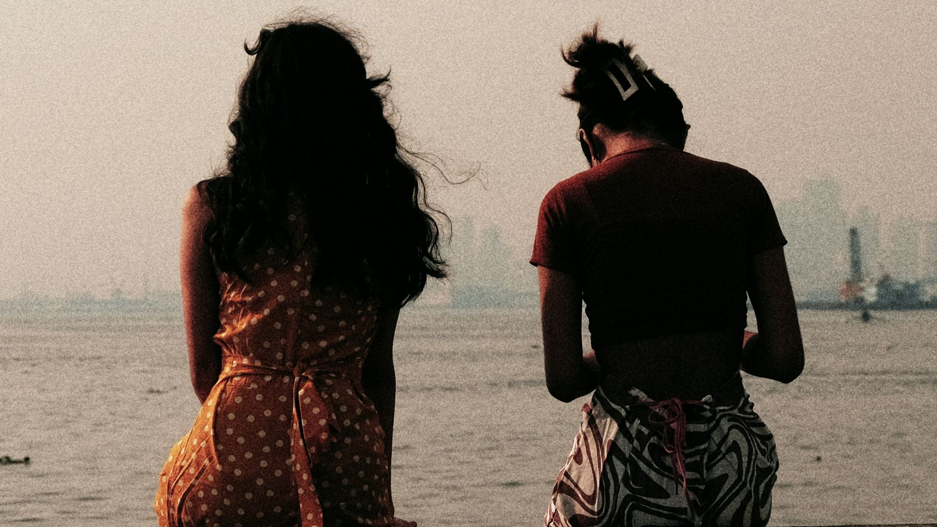 a man and woman sitting on a ledge looking at the water