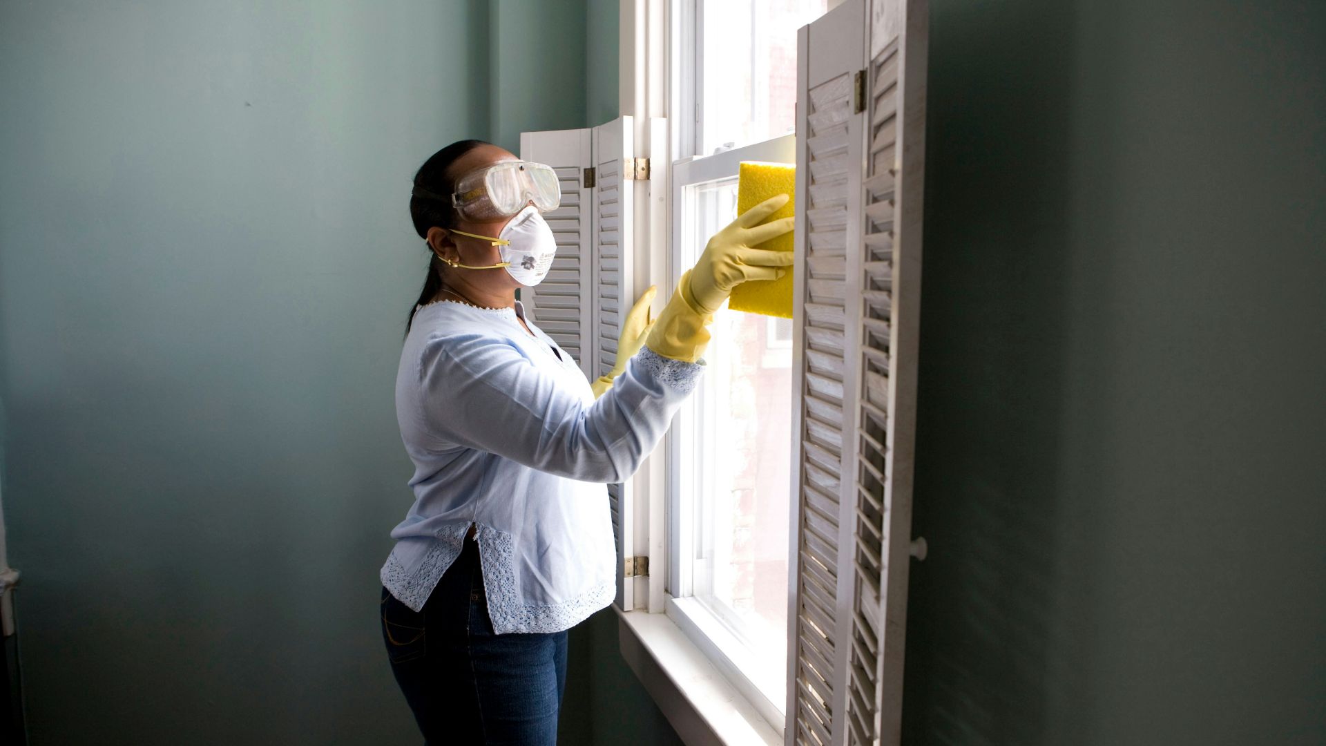 woman in white long sleeve shirt and blue denim jeans standing beside white wooden framed glass