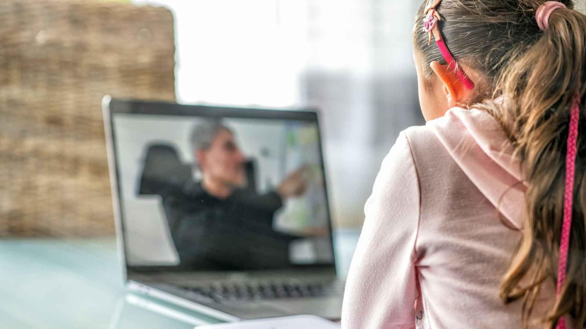 woman in pink long sleeve shirt sitting in front of macbook pro