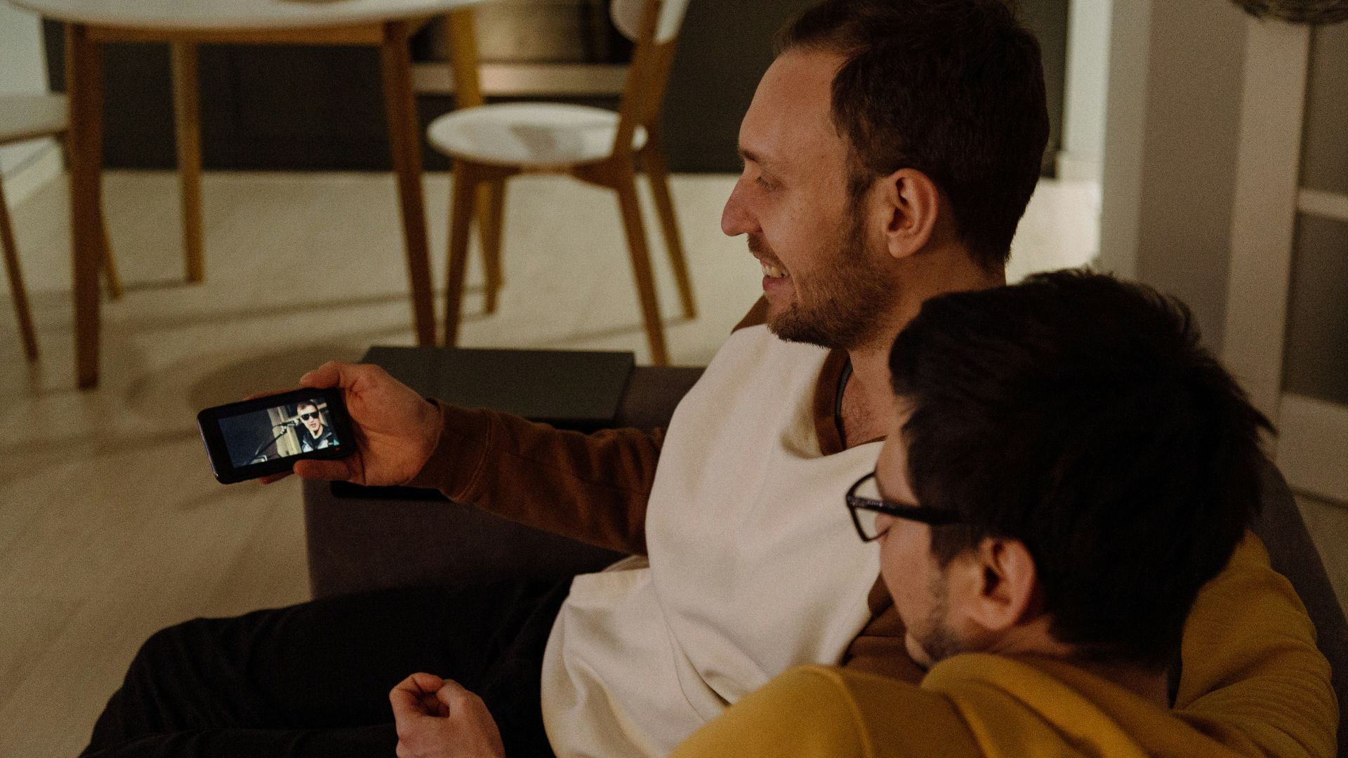 two sitting men watching from smartphone