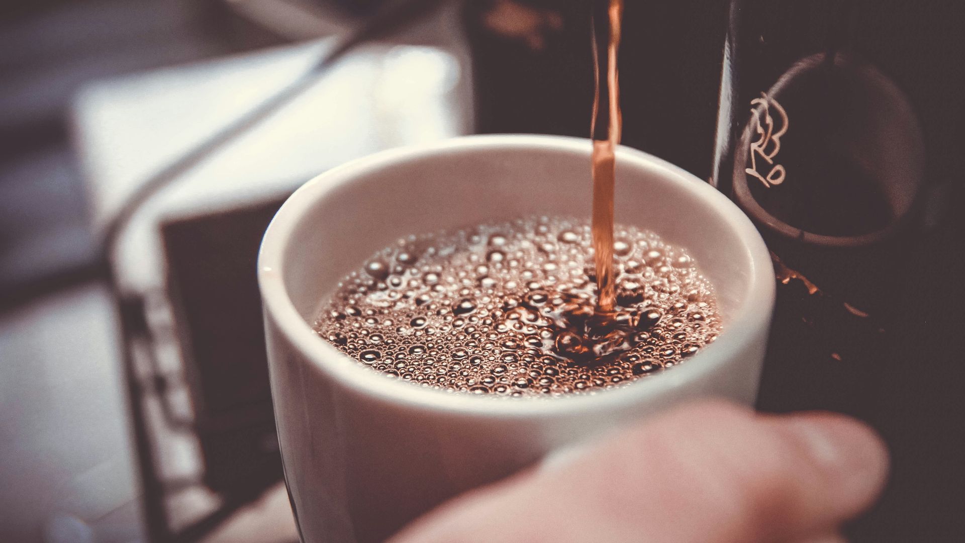 person holding white cup pouring coffee