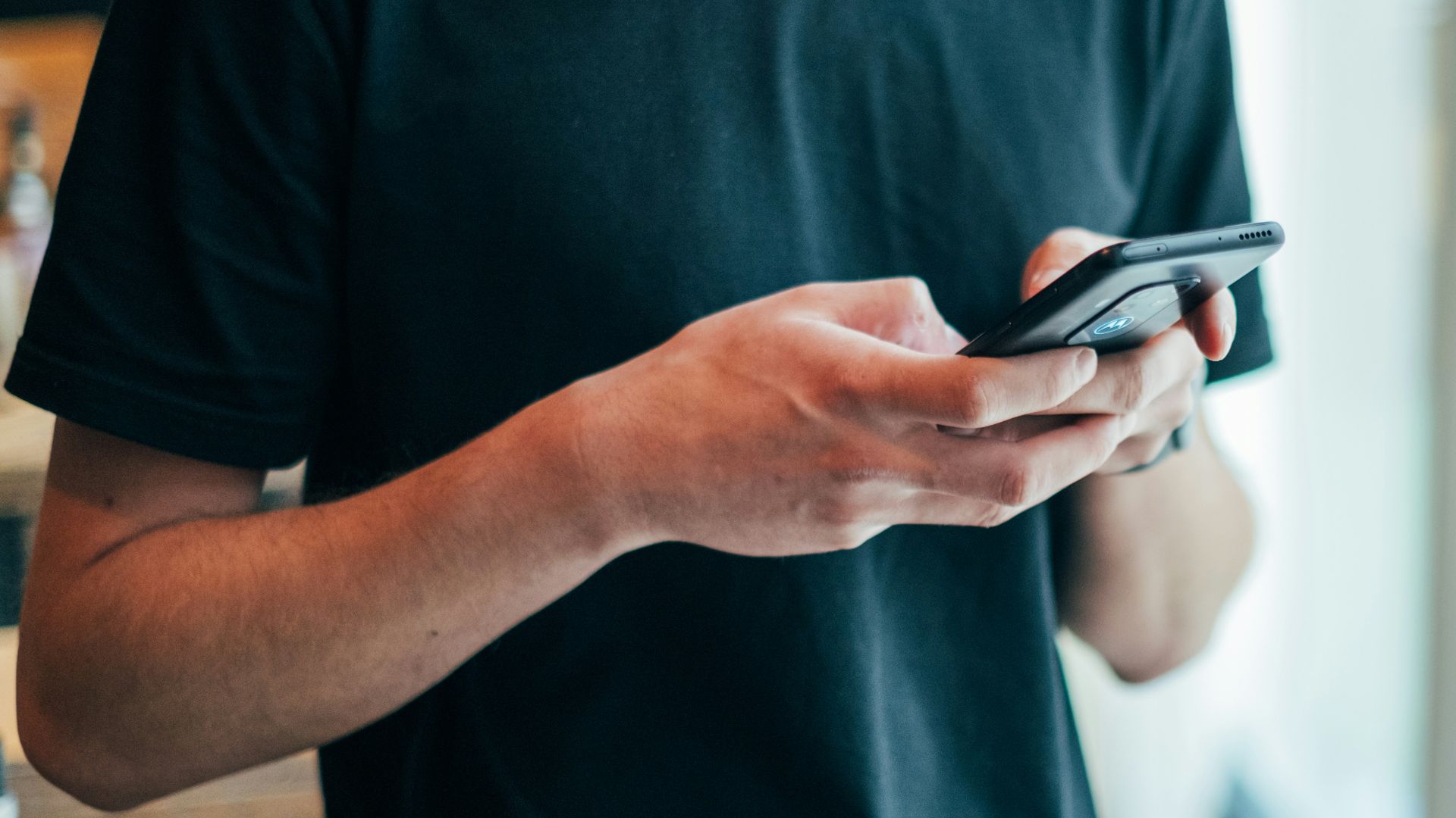 man in black crew-neck top using smartphone