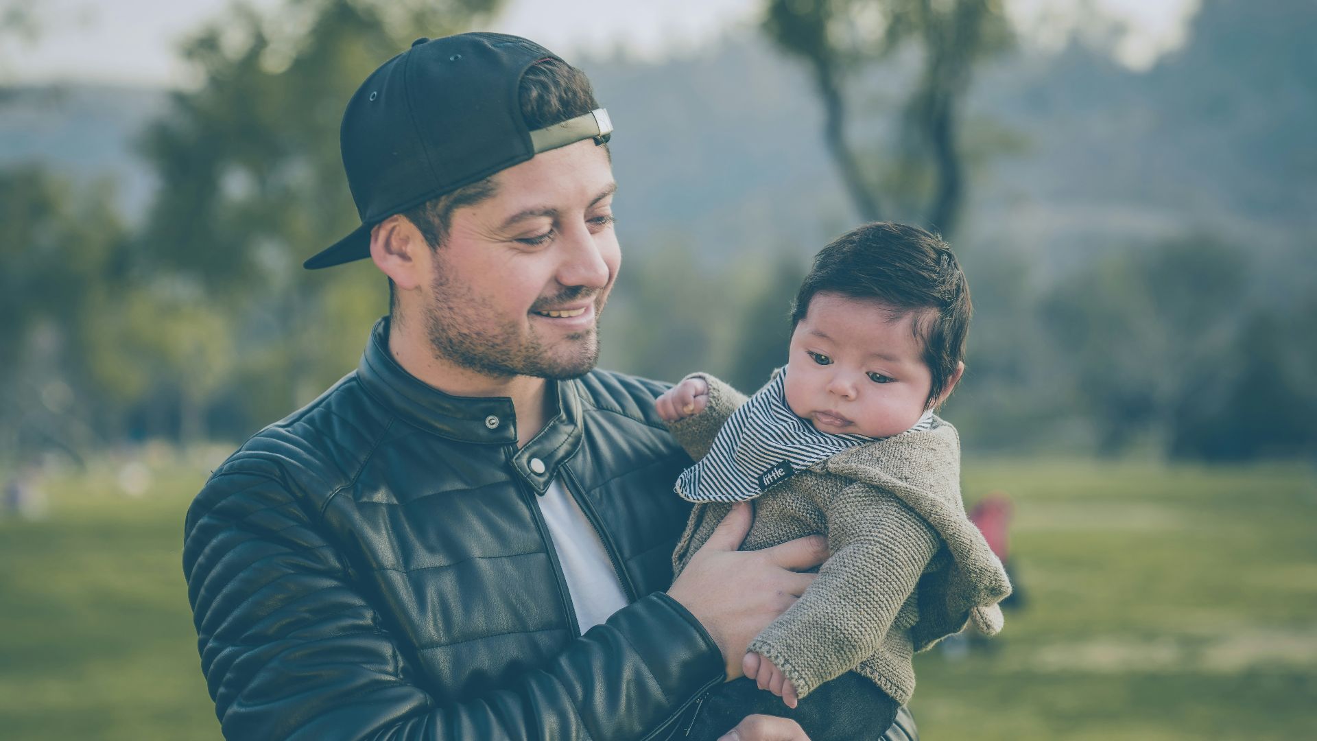 man wearing black leather jacket holding baby