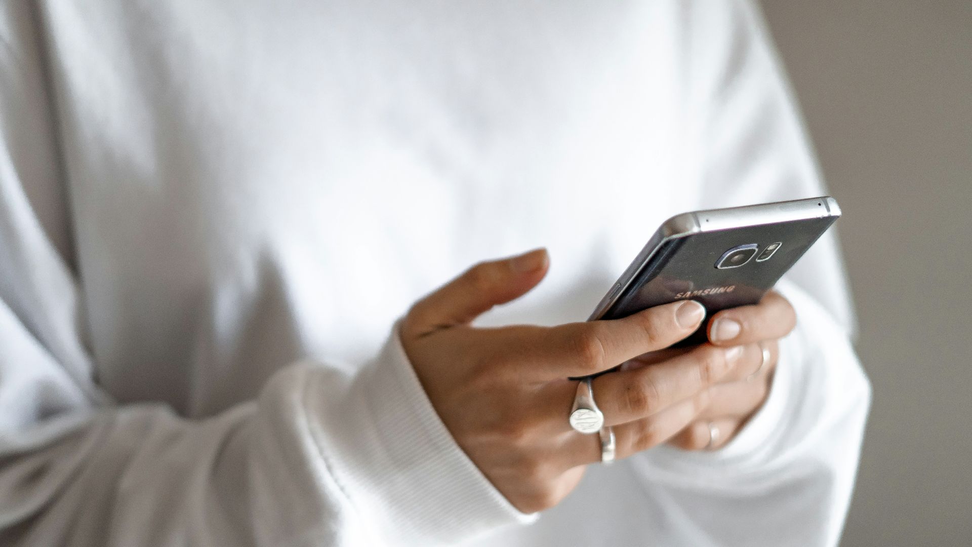 person in white long sleeve shirt holding black smartphone