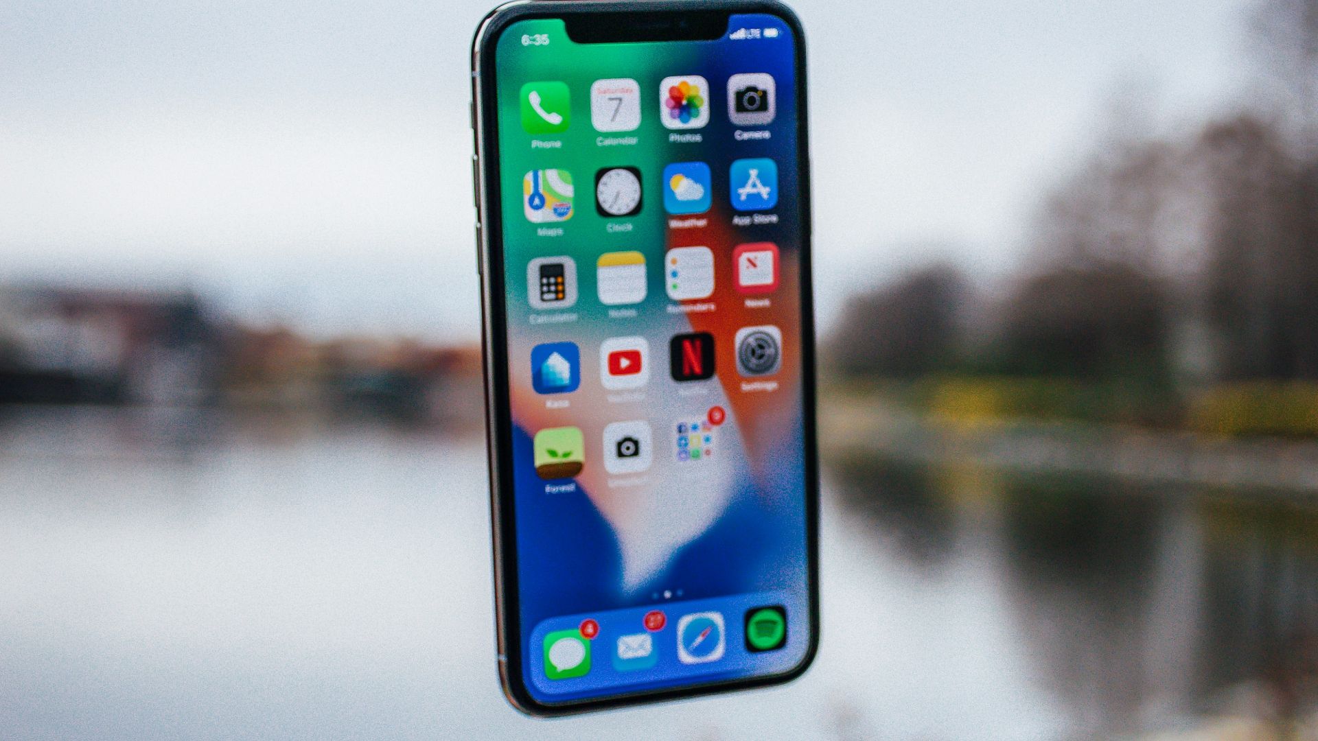 silver iPhone X floating over open palm