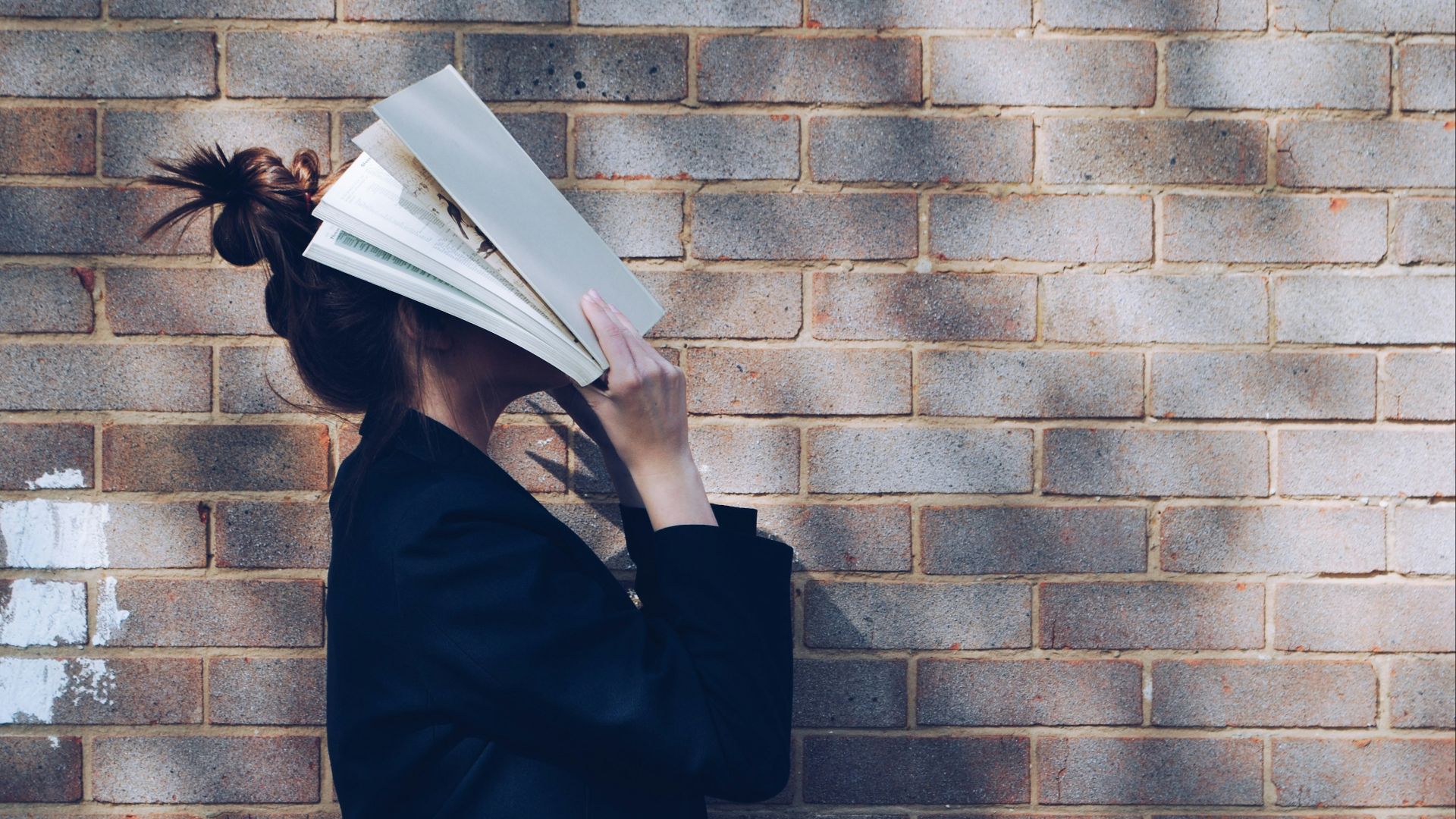 woman covering her face with white book