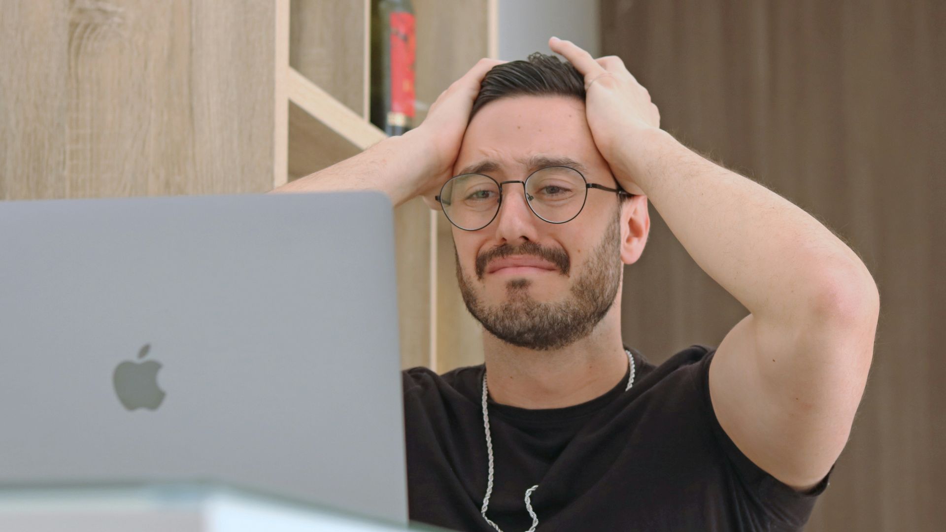 a man with glasses is looking at a laptop