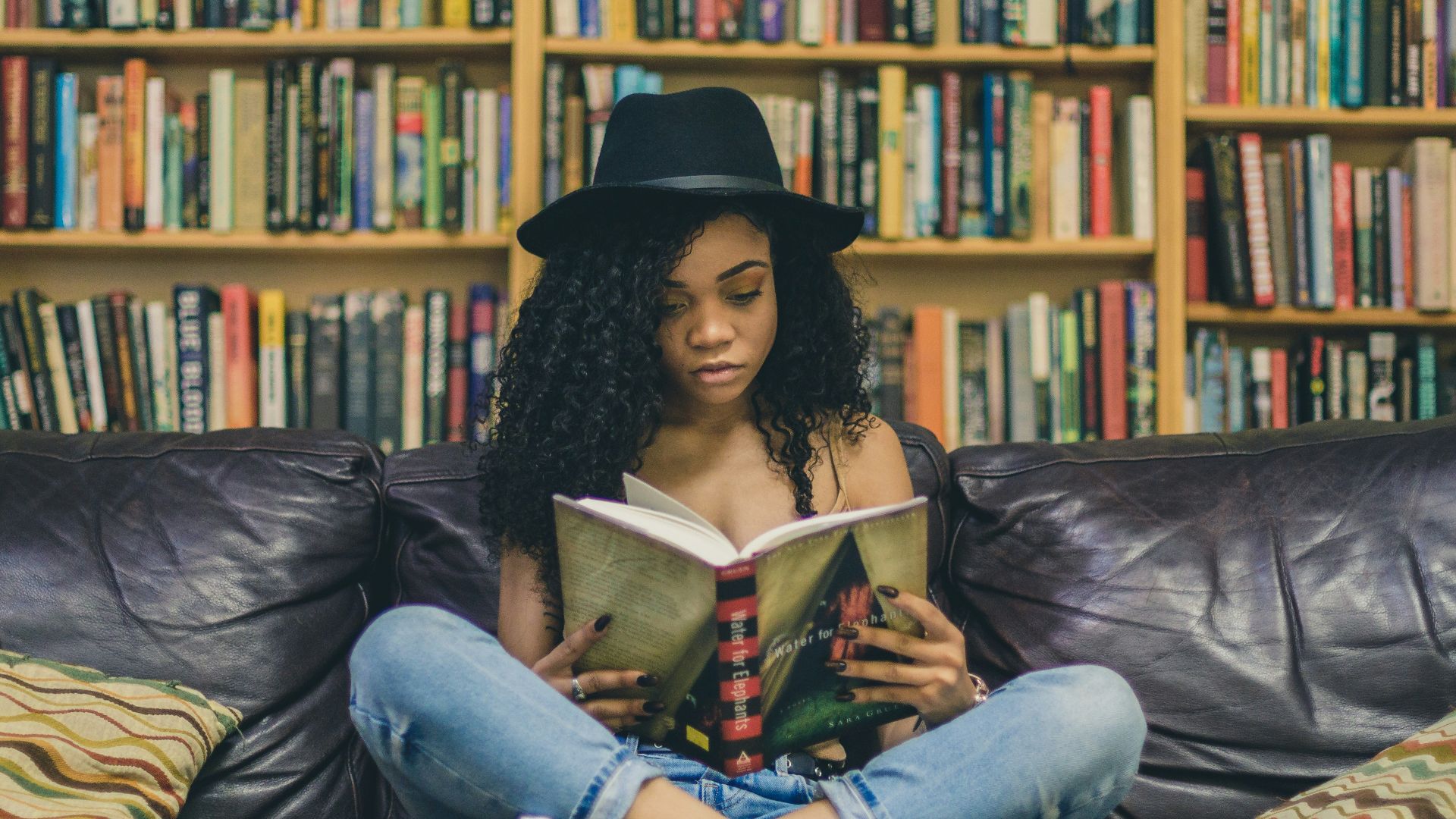 woman reading a book while sitting on black leather 3-seat couch