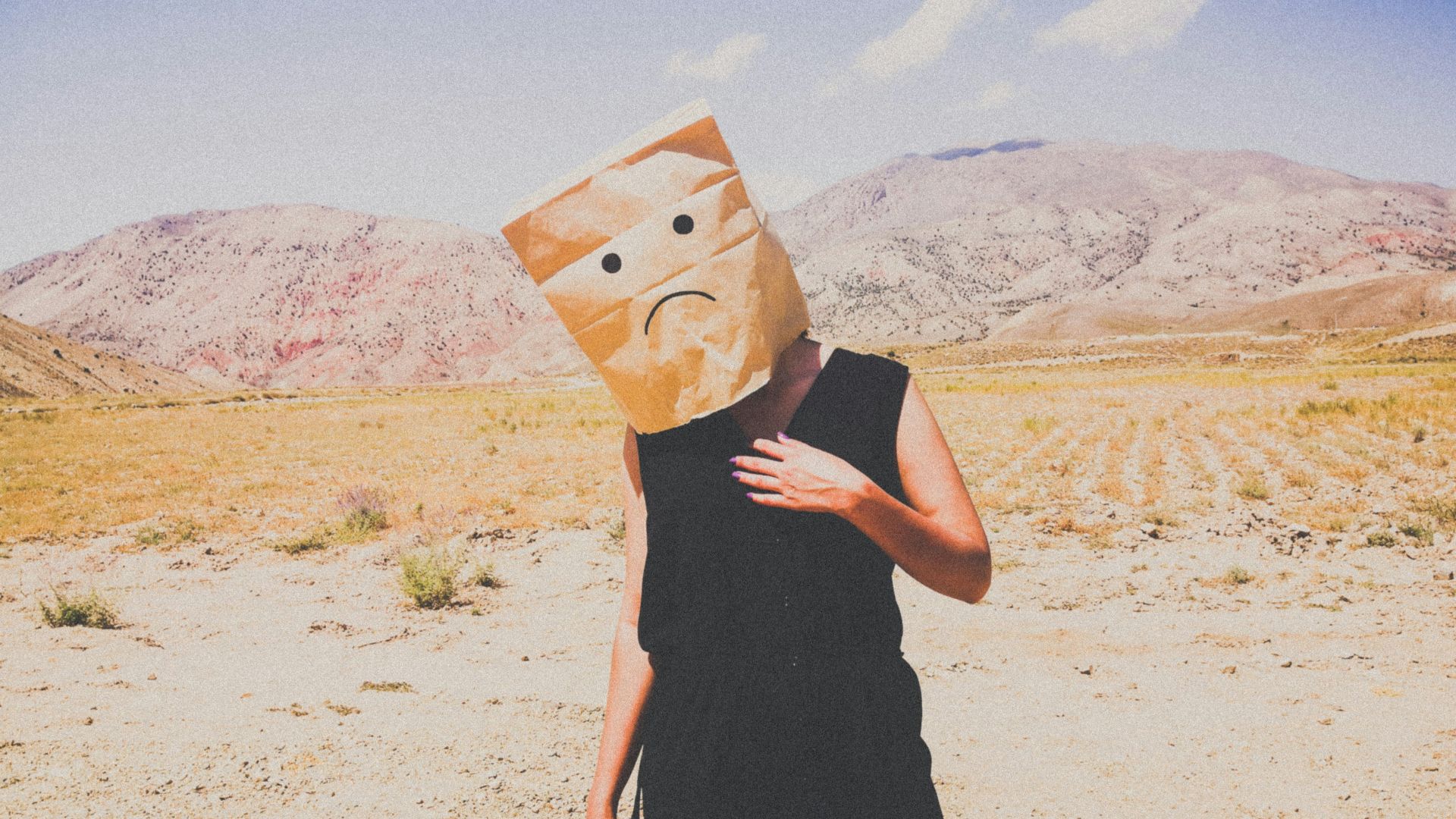 woman in black dress holding brown paper bag