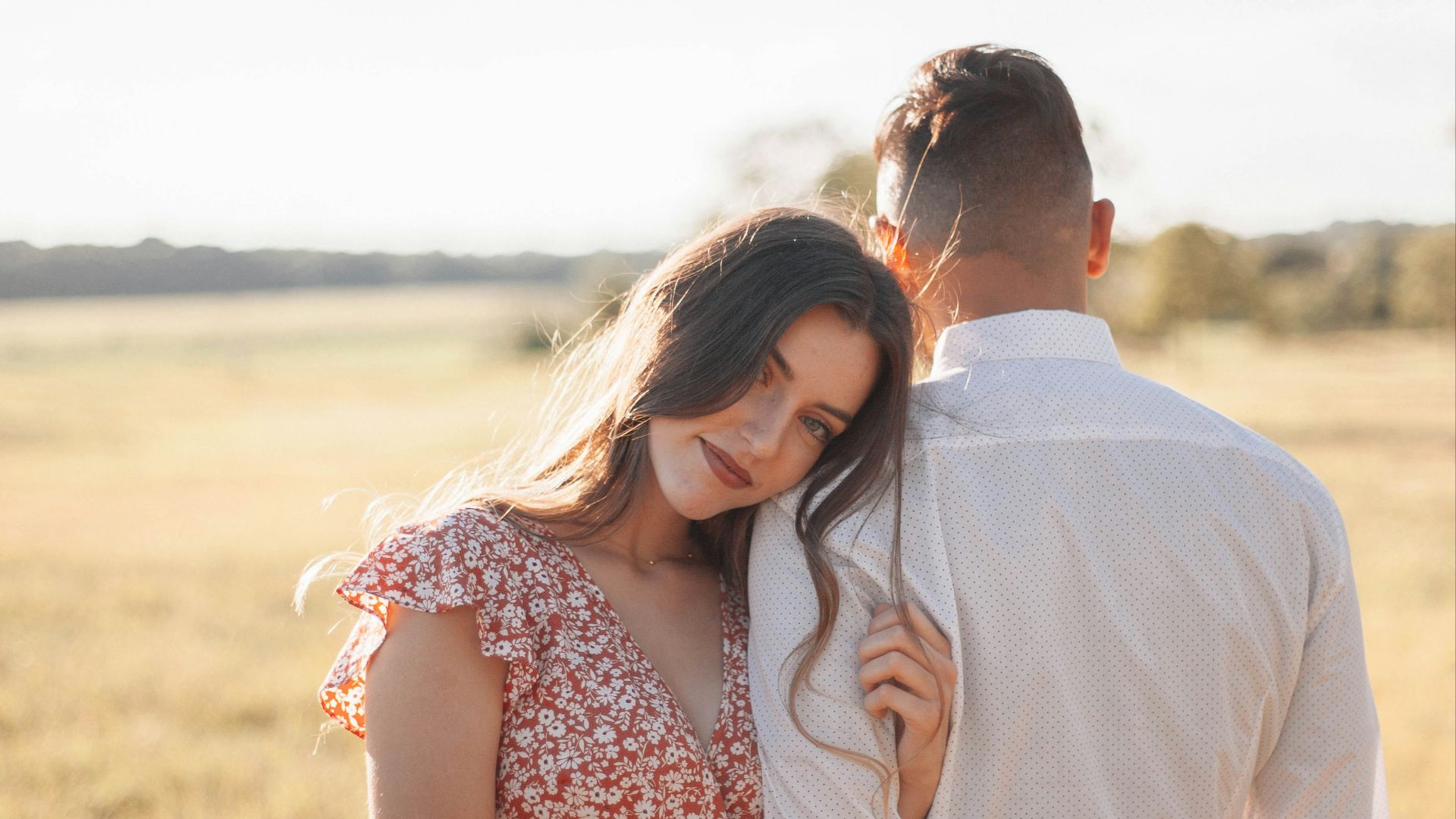 man in white dress shirt kissing woman in red and white floral dress